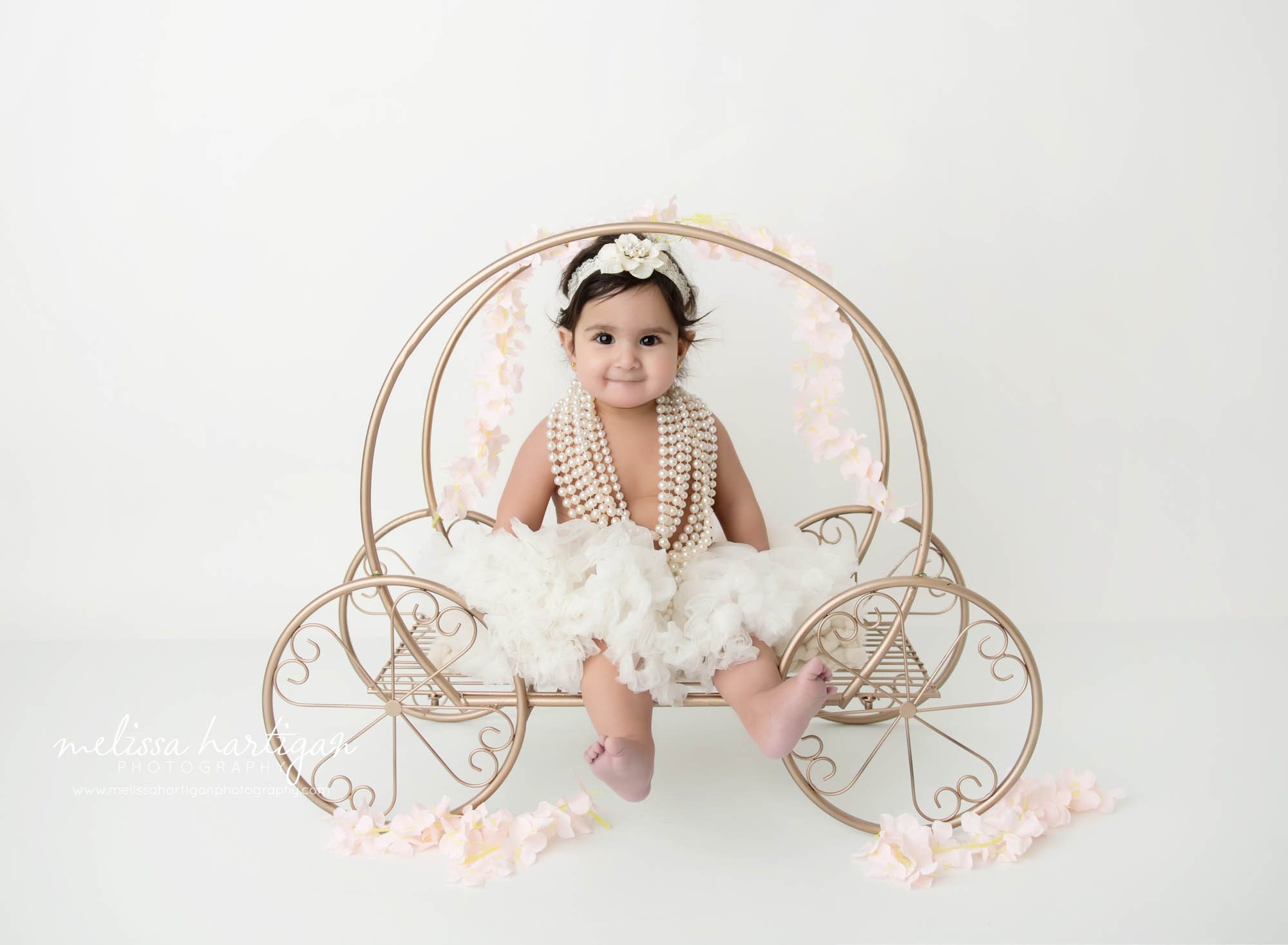 baby girl sitting on cinderella carriage prop 