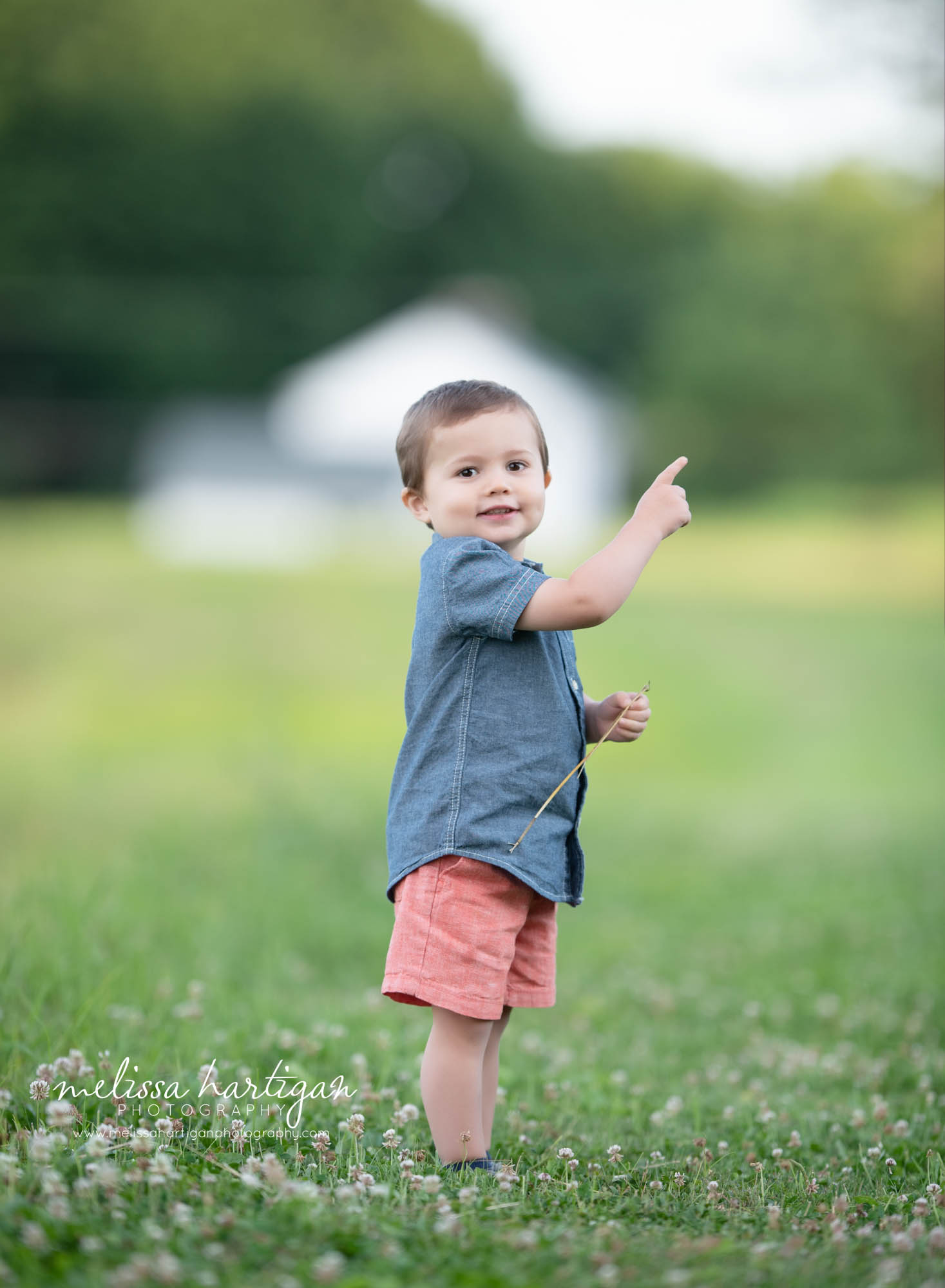 little boy showing parents and pointing outside in field