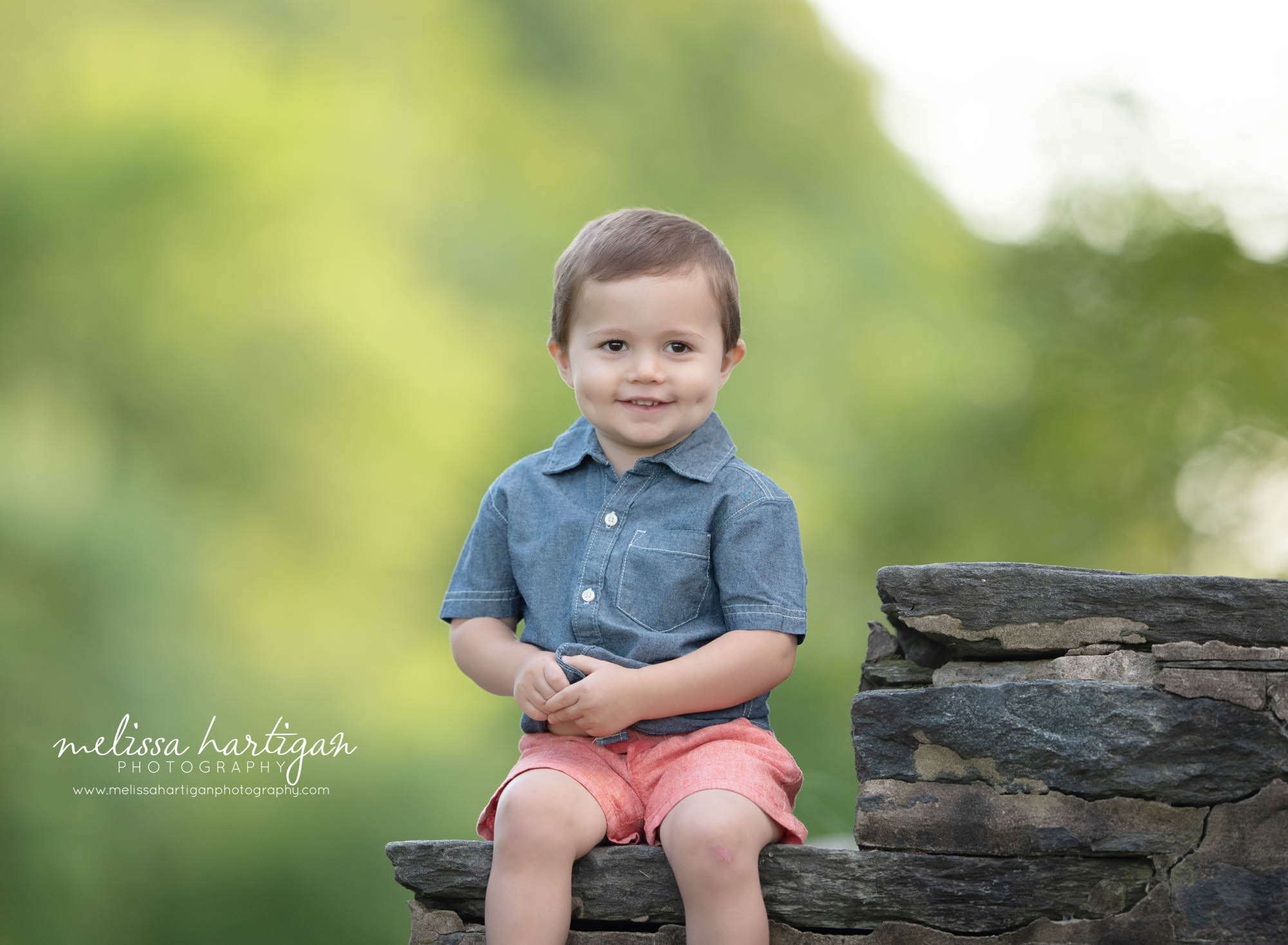 two year old boy sitting on rock in park CT milestone photography