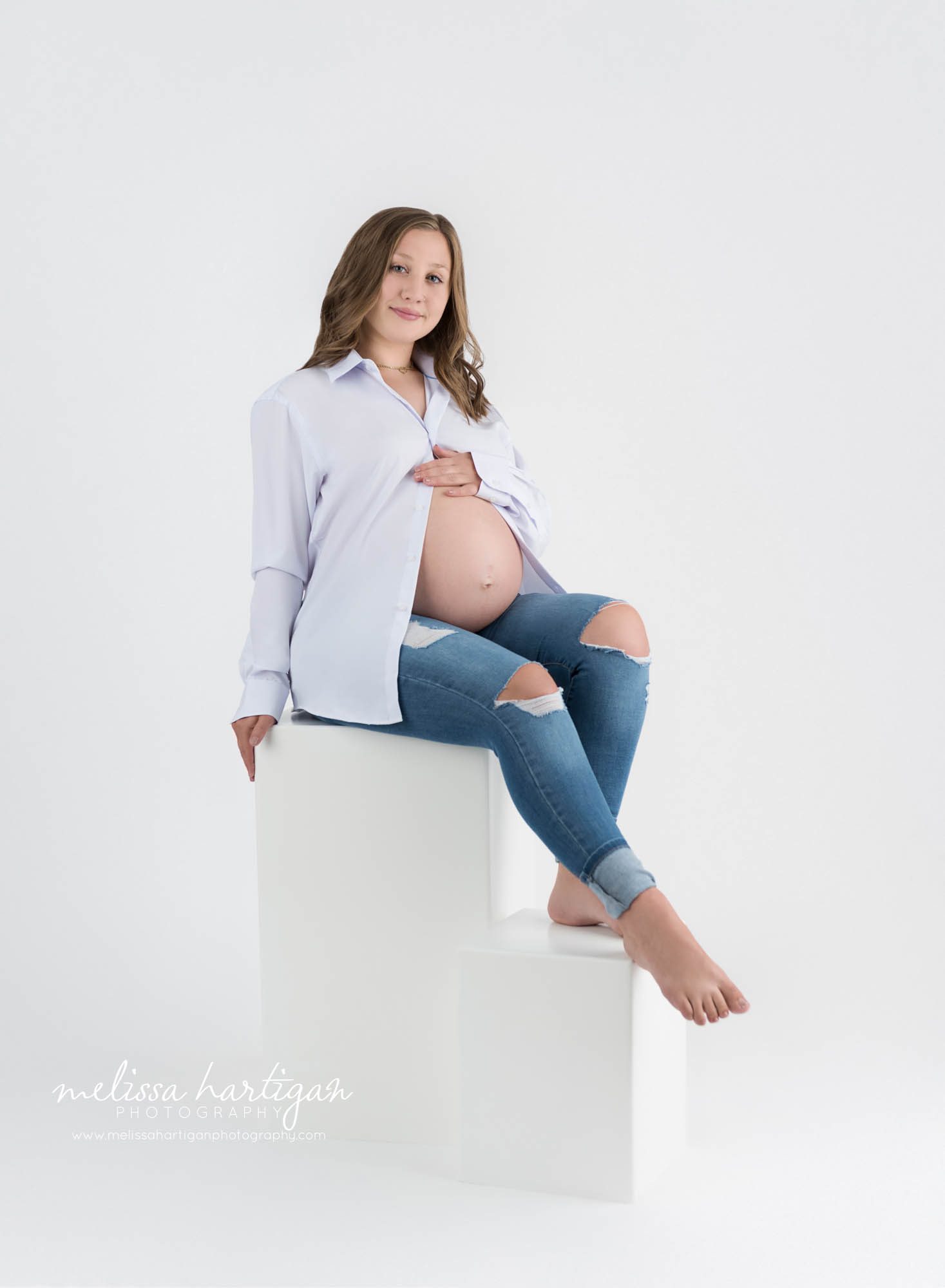 pregnant mom sitting on white block studio maternity