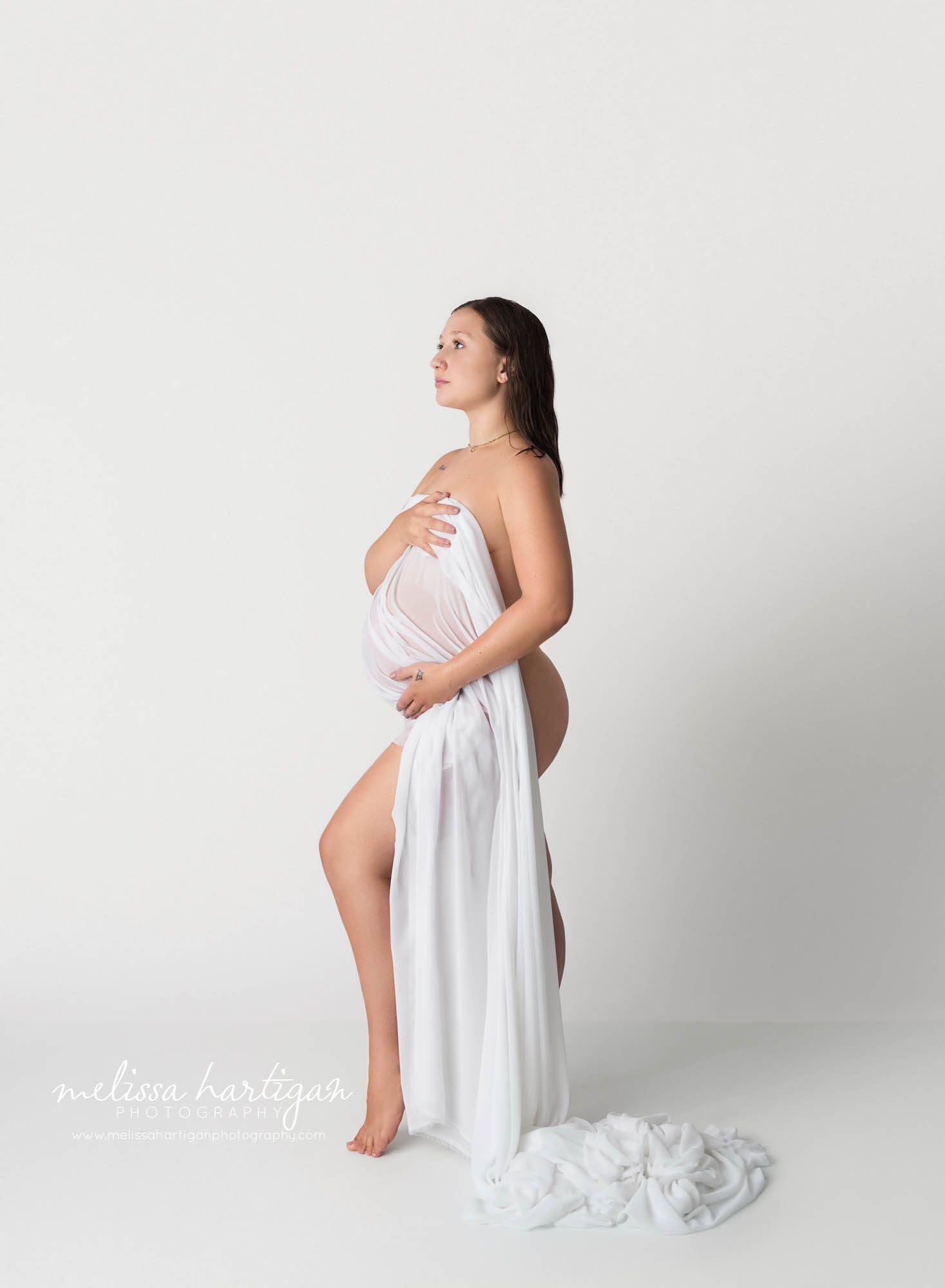 standing maternity pose pregnant mom holding fabric over baby bump