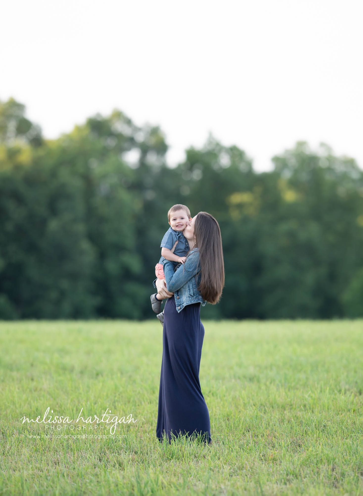 mom giving son kiss on cheek outdoor family session CT
