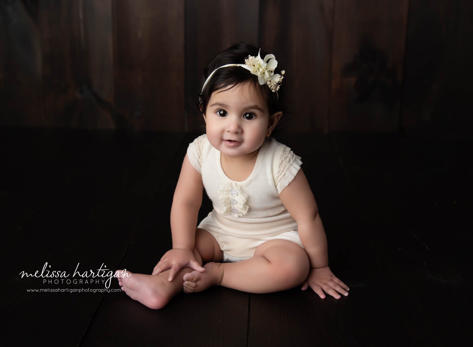 baby girl sitting on wooden boards in studio milestone session