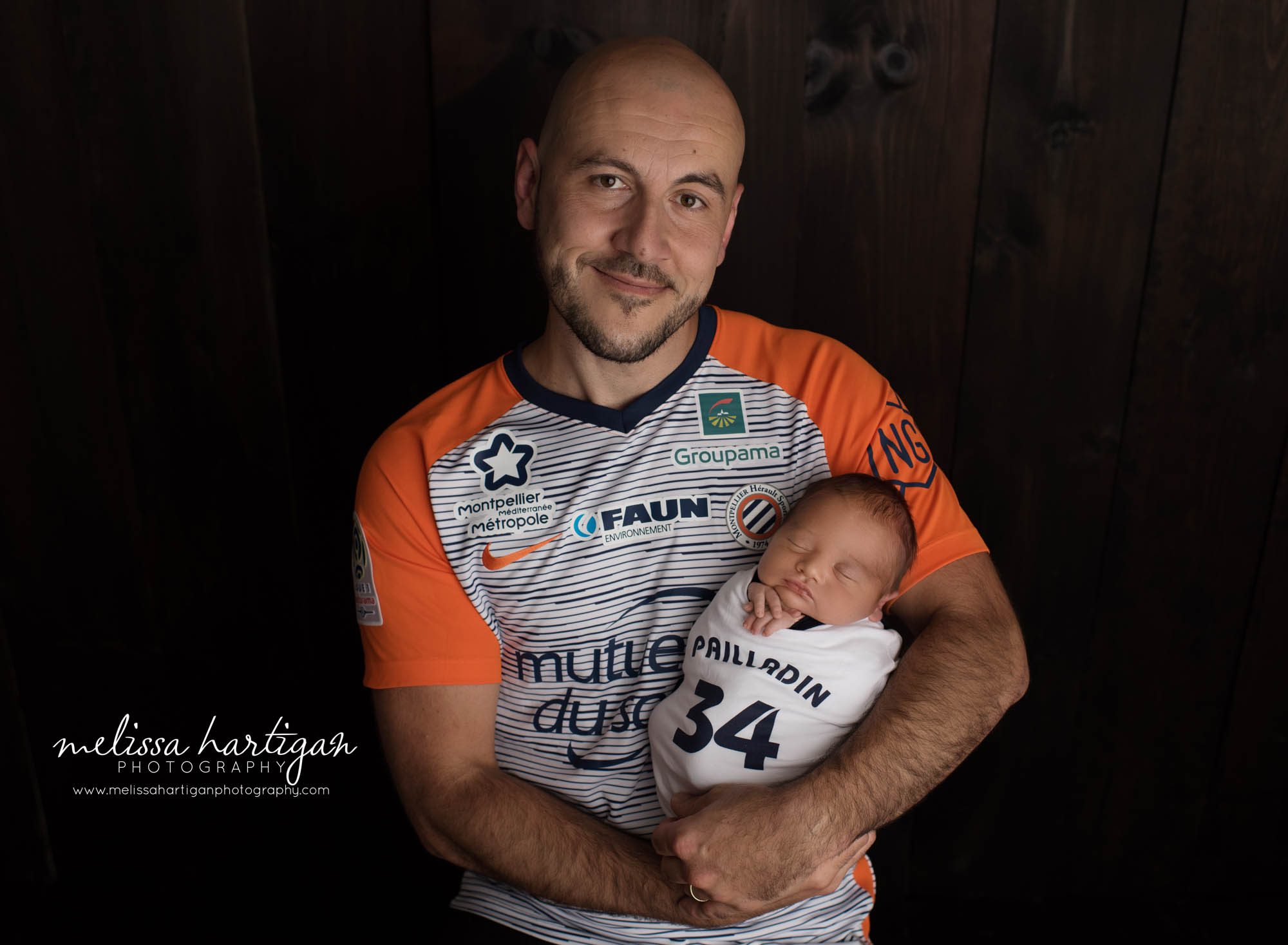 dad holding newborn son wearing monpellier france shirt