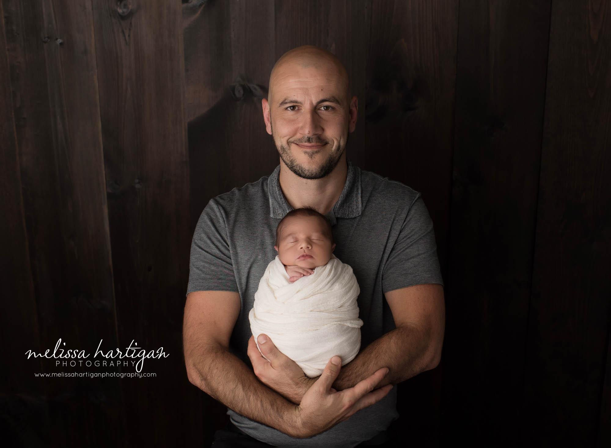dad holding newborn son in front of his chest