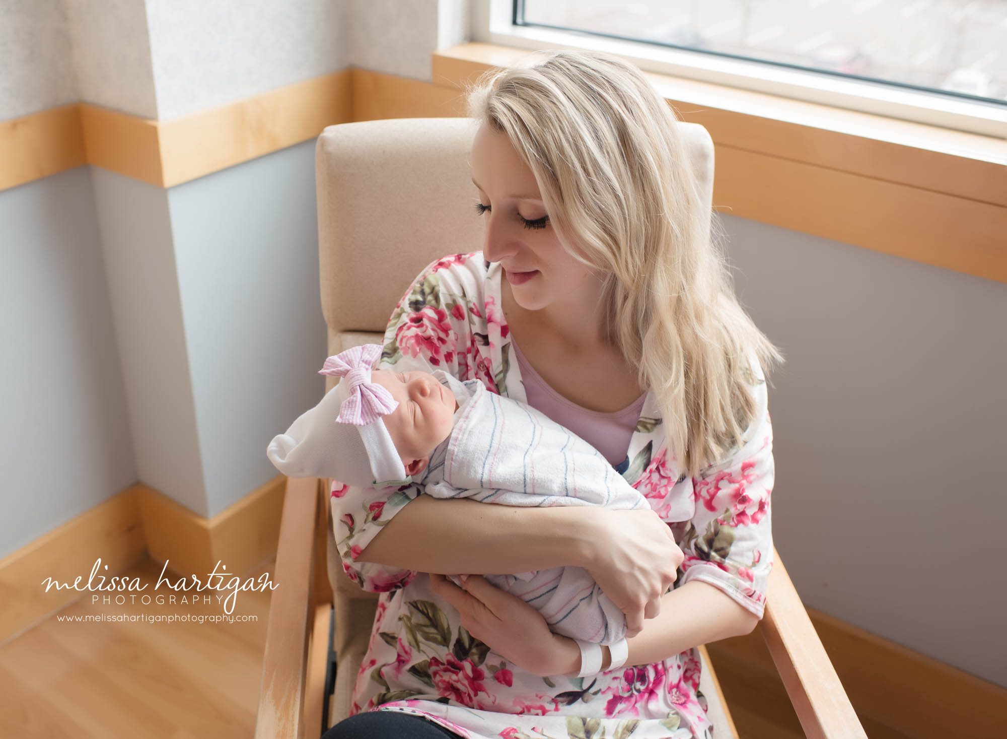 mom sitting in hospital chair holding newborn daughter