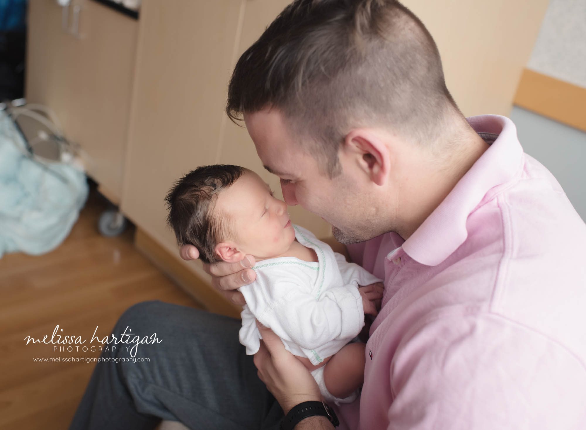 dad holding newborn daughter touching nose to nose