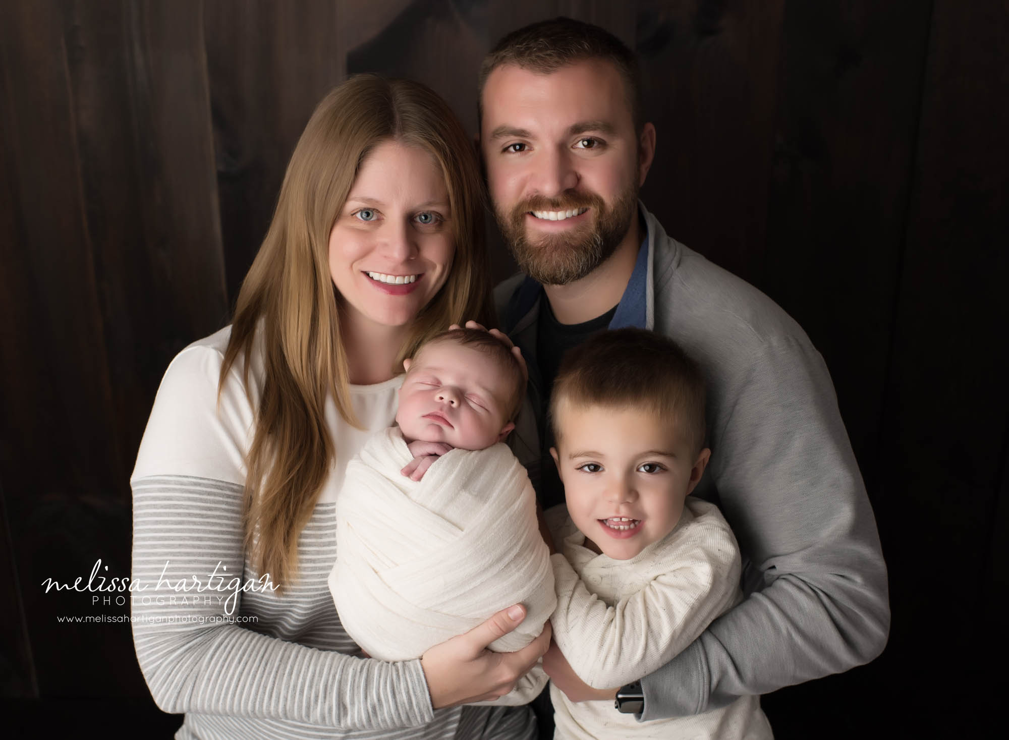 newborn baby boy being held by mom dad and big brother for family pose Connecticut newborn and family photographer