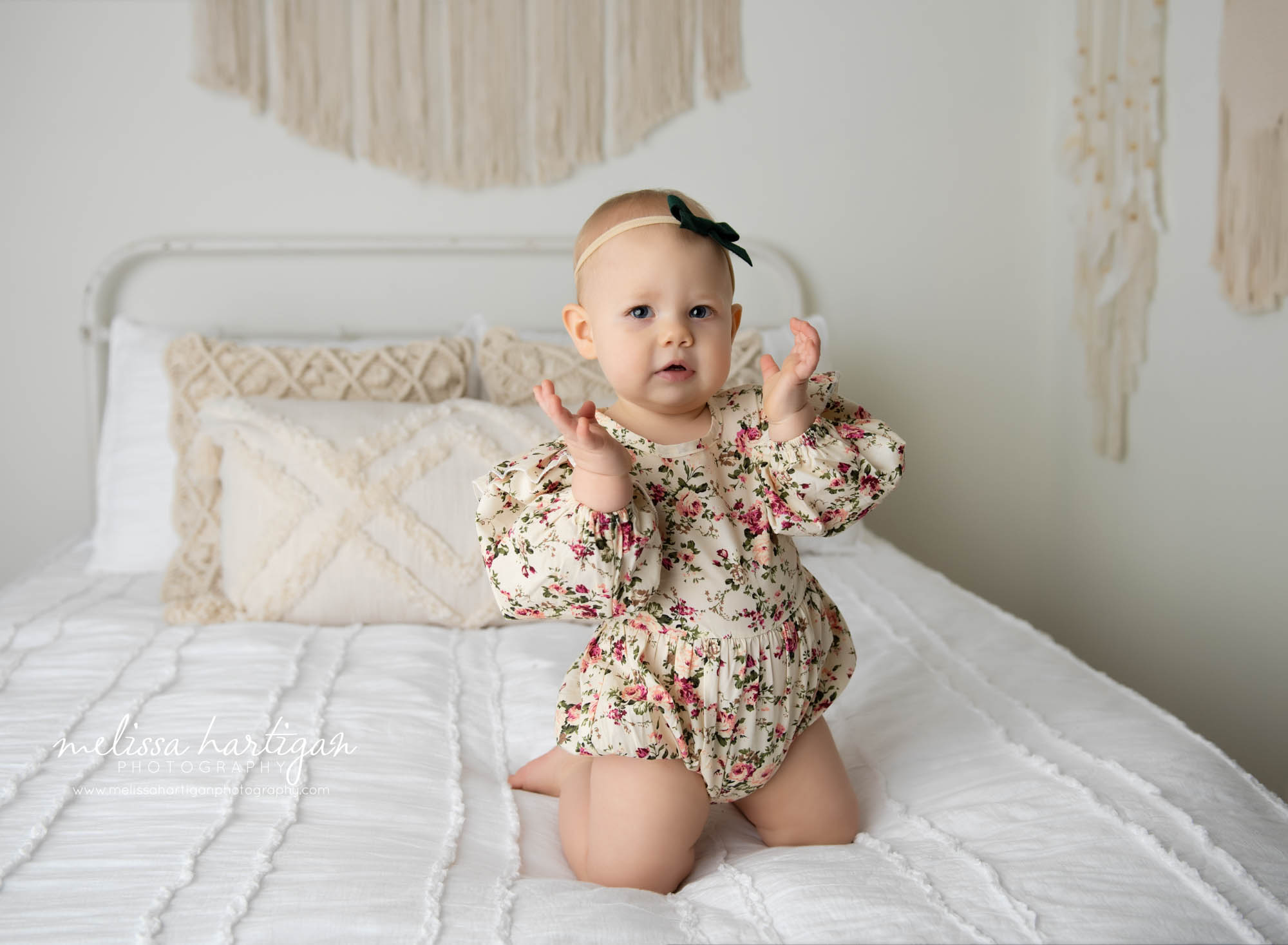 baby girl kneeling on bed clapping