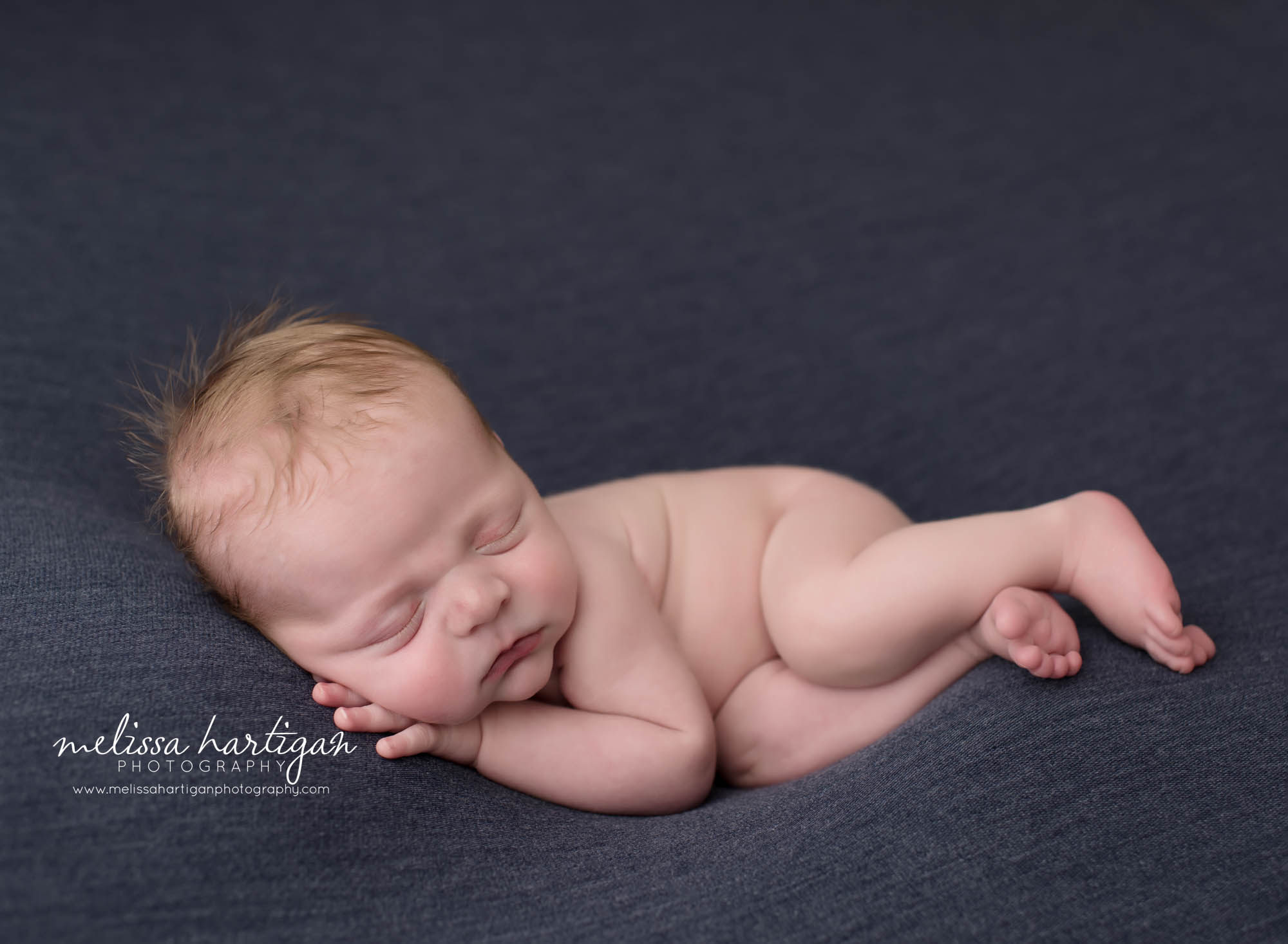 newborn baby boy posed on blue backdrop posed on side sleeping newborn photographer east windsor