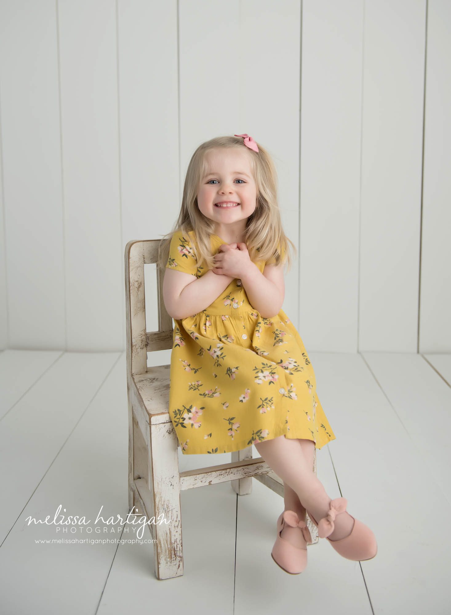 little girl wearing yellow dress sitting on wooden chair in studio tolland ct milestone photography