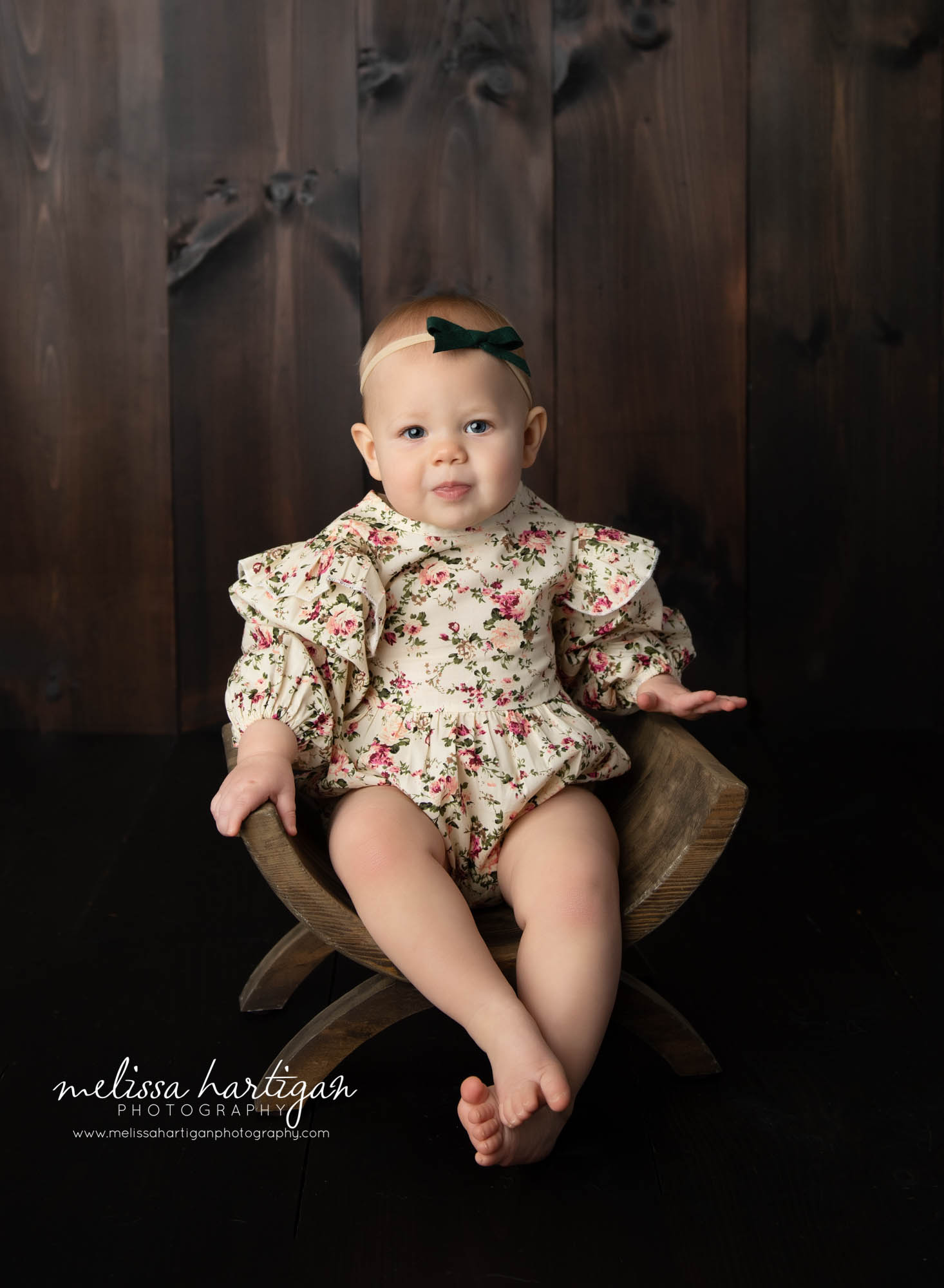 baby girl sitting in wooden bench wearing floral outfit masnfield CT baby photography