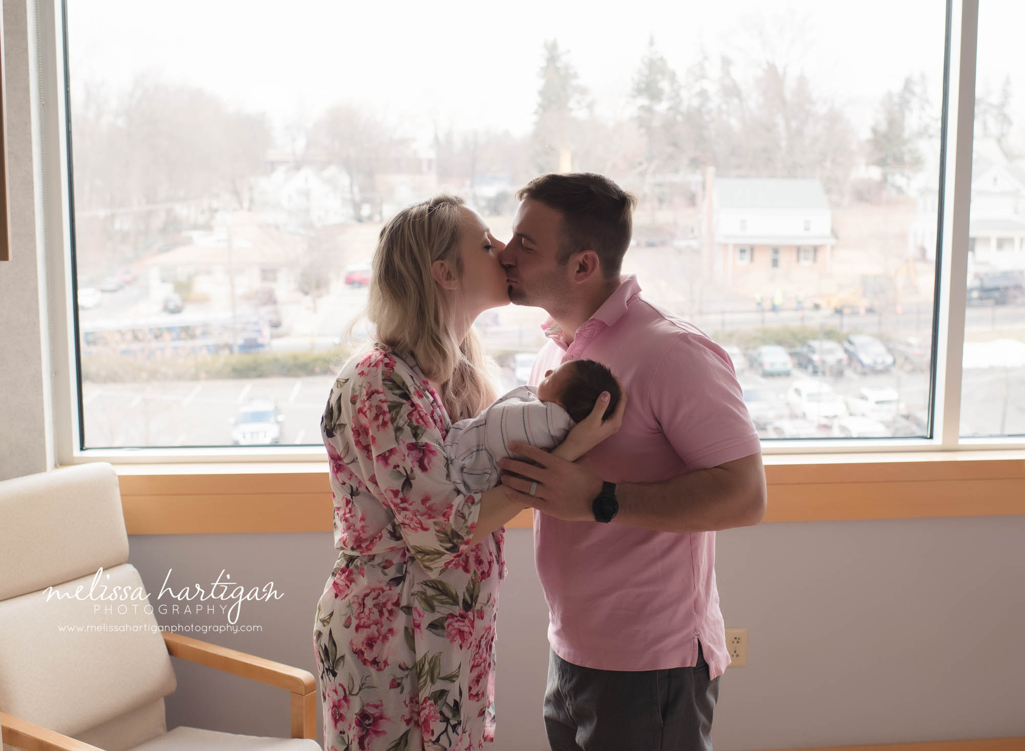 mom dad sharing kiss holding newborn daughter tolland county CT newborn baby photographer