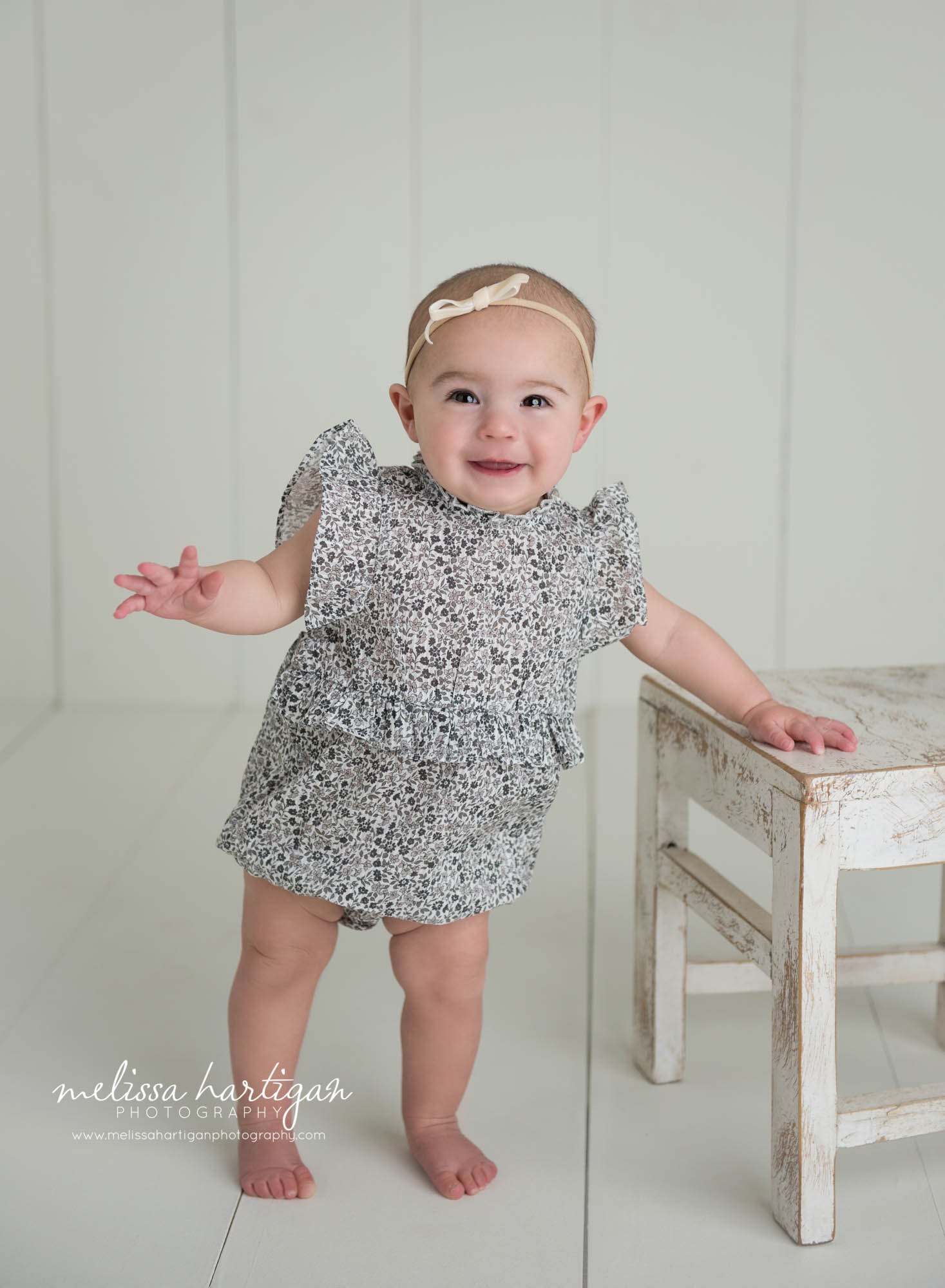 baby girl standing next to wooden chair prop CT baby milestone photos
