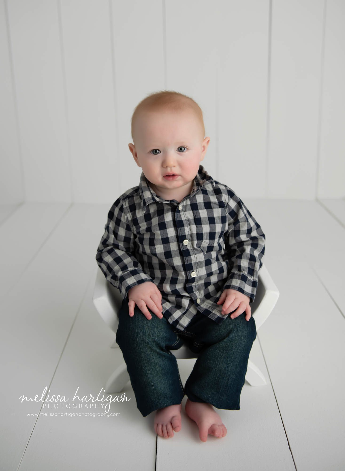 baby boy sitting on curved stool chair in photography studio CT