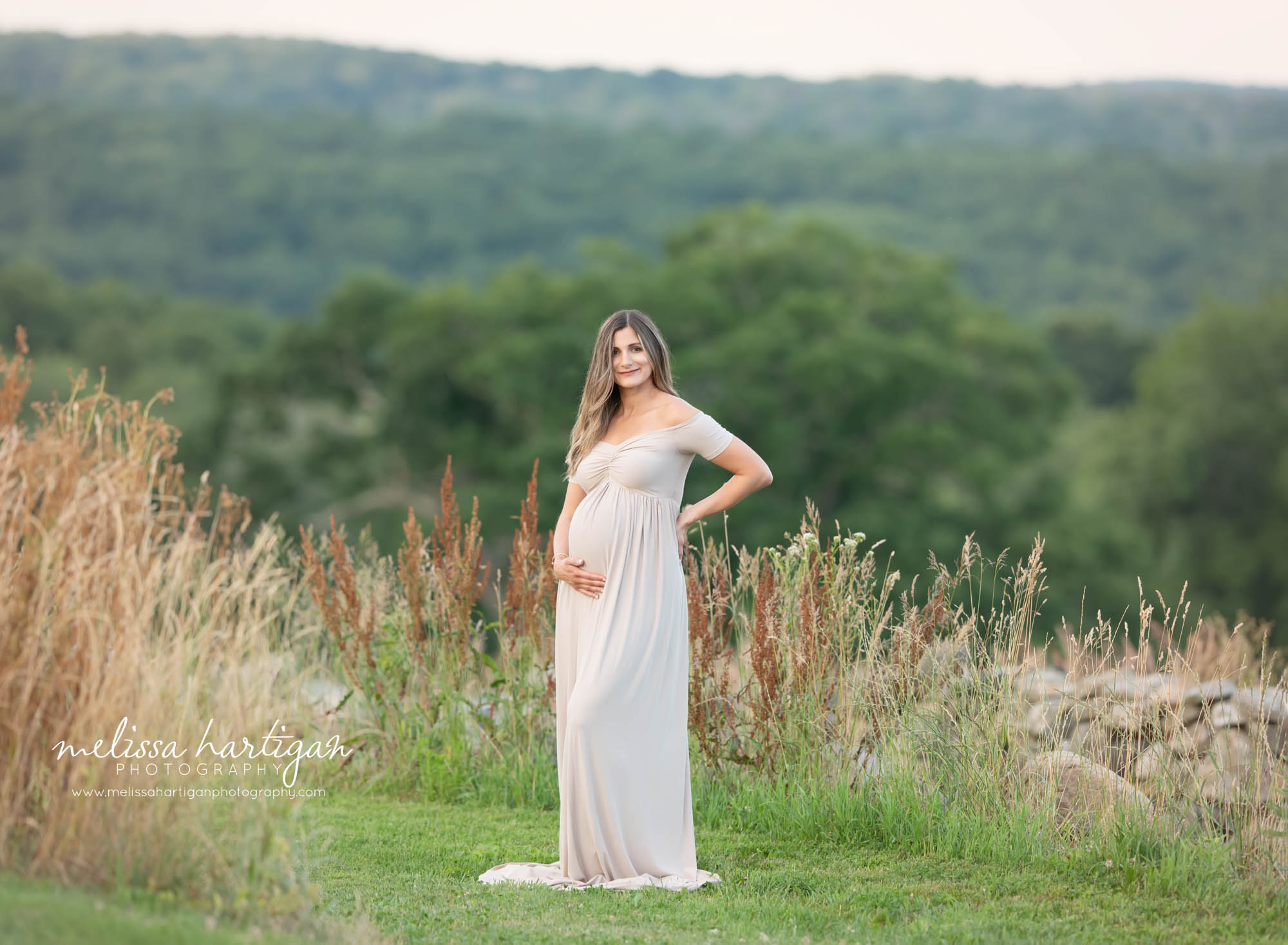 mom to be wearing long maternity gown standing holding under baby bump CT maternity photographer