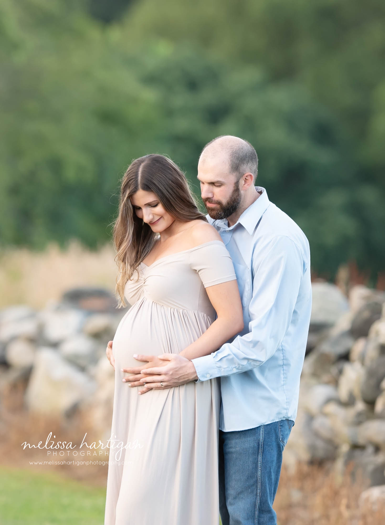 expectant couple holding hands together on side of baby bump