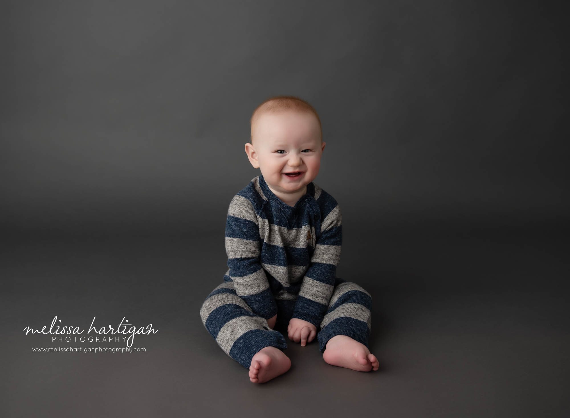 baby boy sitting on gray paper backdrop in sitting up milestone photography session glastonbury CT baby photography