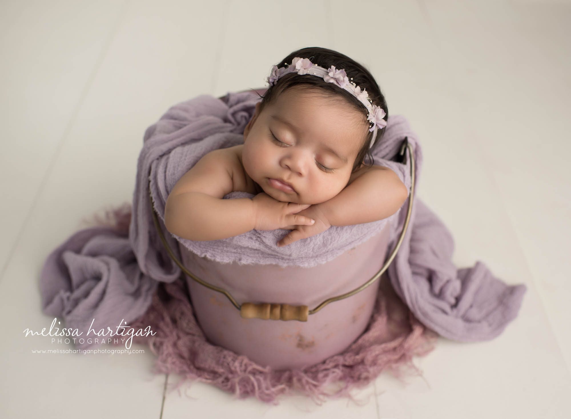 newborn baby girl posed in soft purple metal bucket