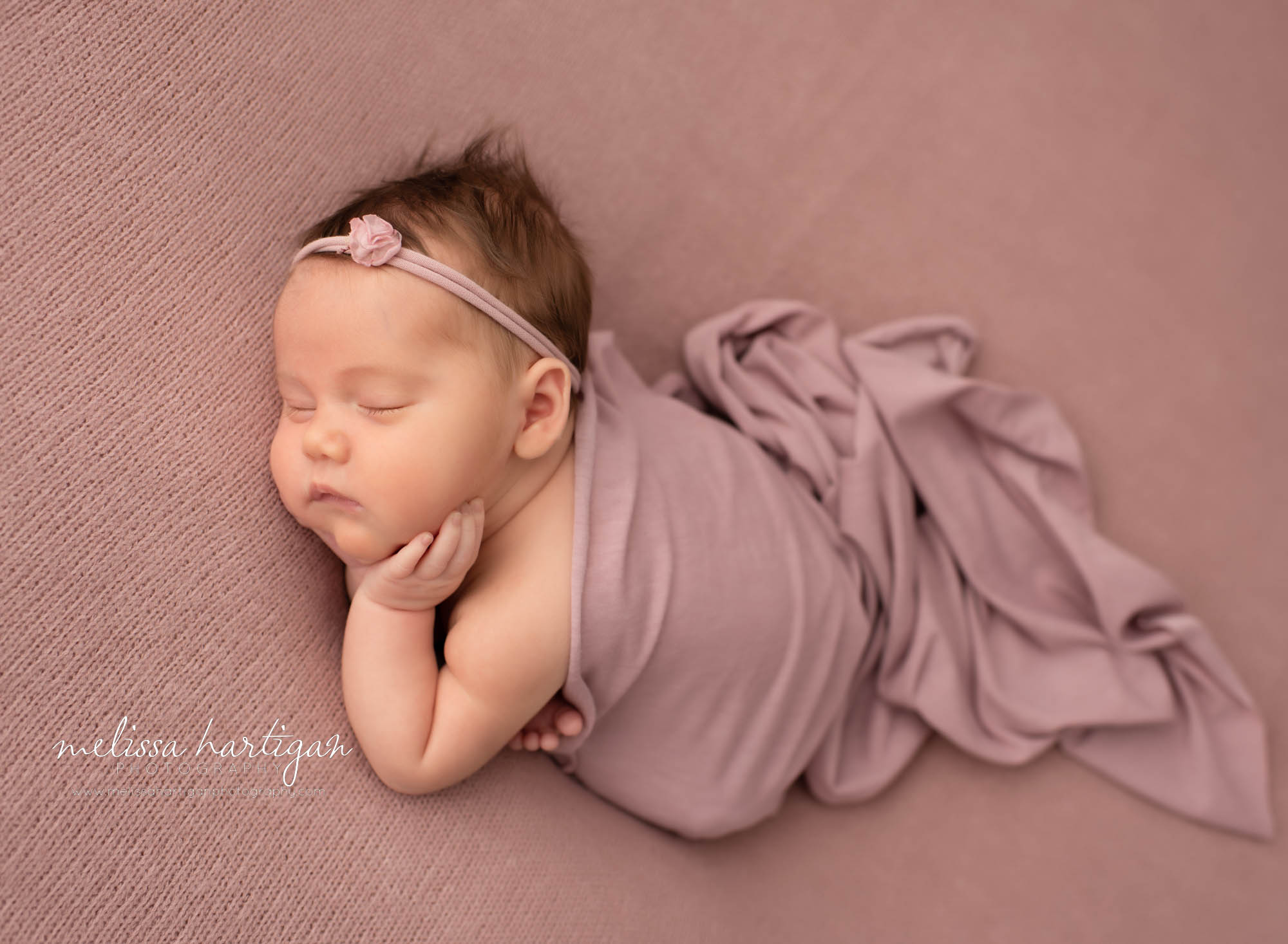 newborn baby girl posed on tummy side with dusty rose colored fabric draped over her back newborn photographer CT