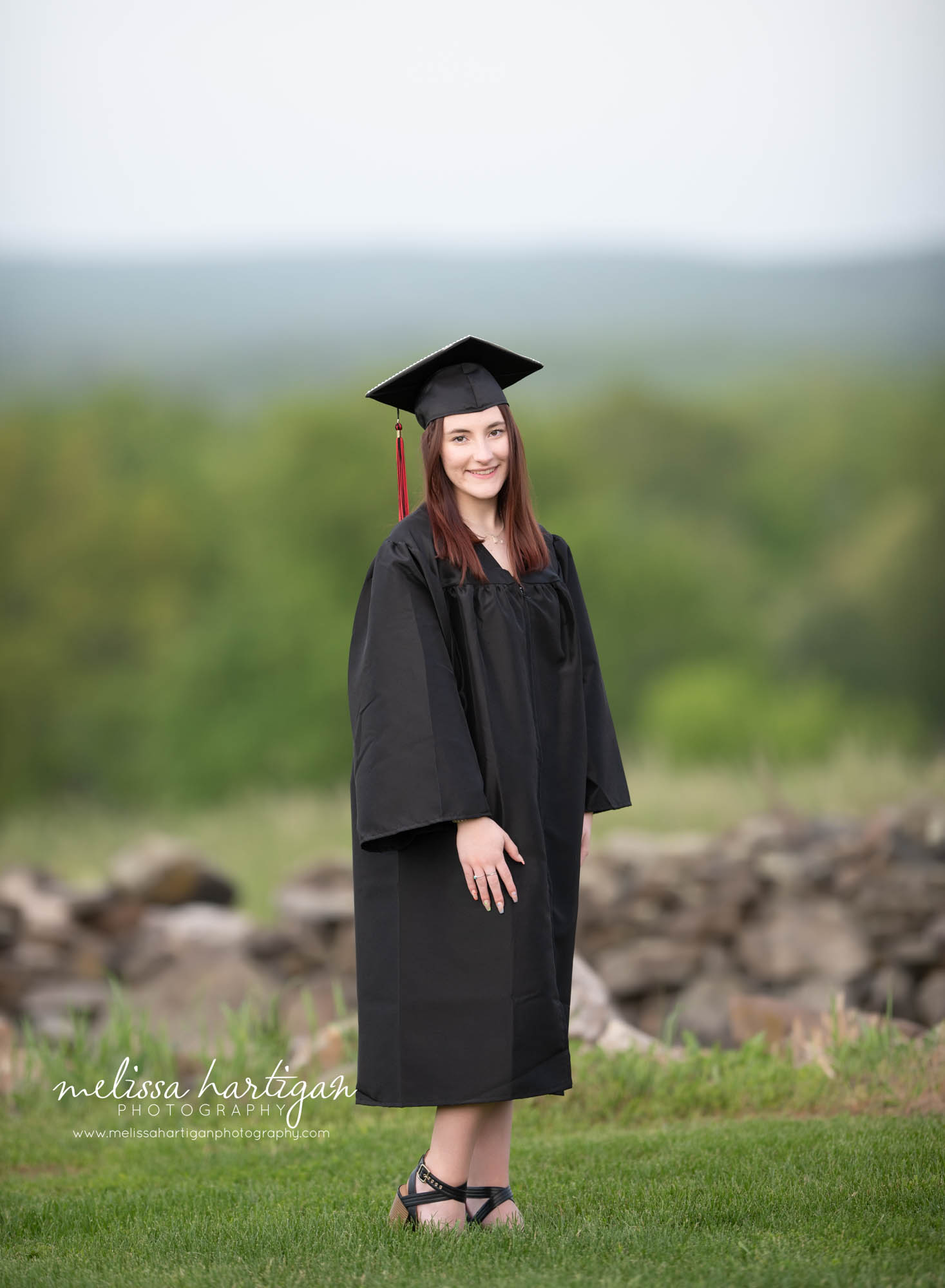 senior teen standing in field wearing graduation cap and gown senior photography CT