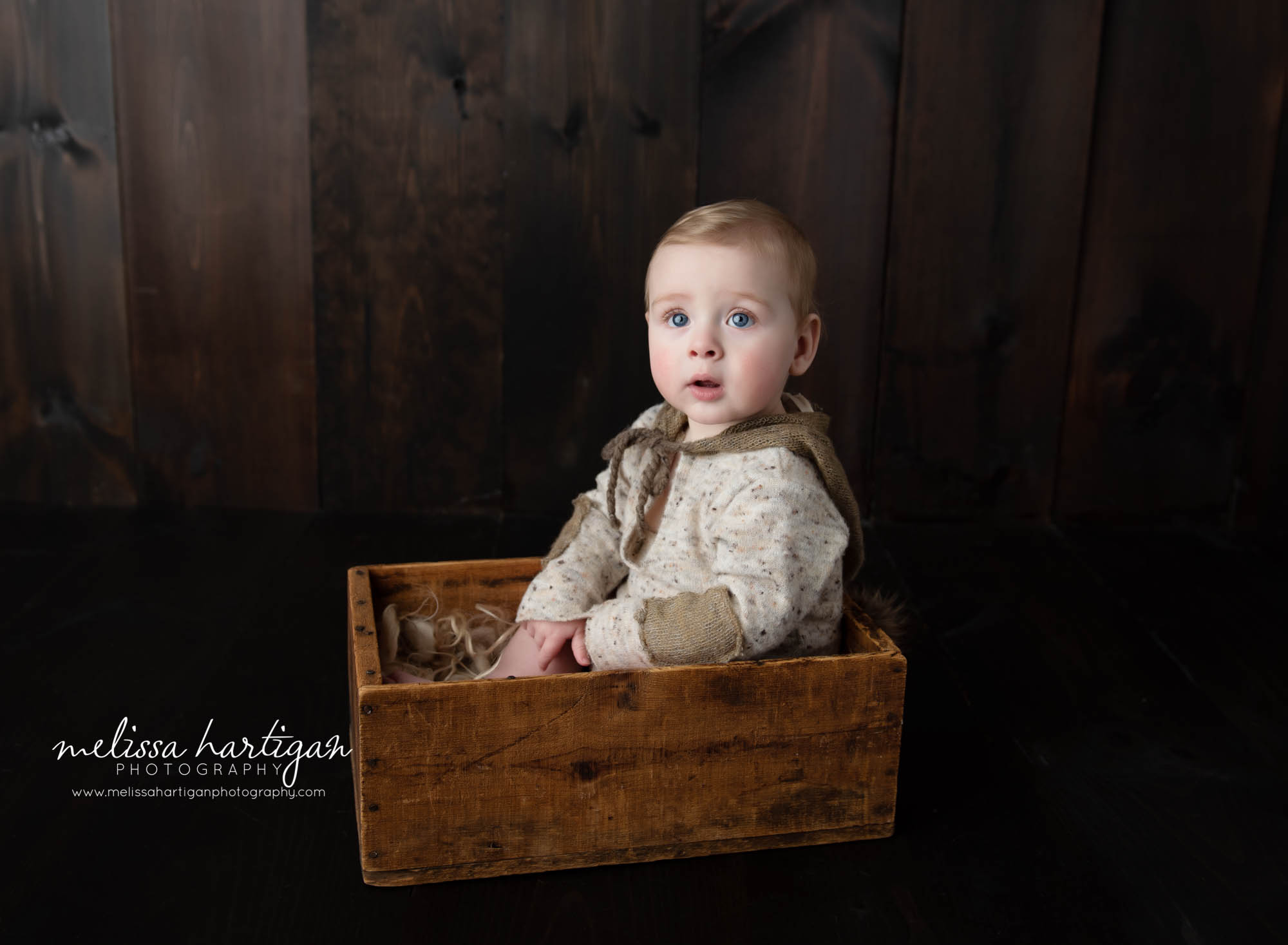 baby boy sitting in wooden box wearing baby boy photography outfit