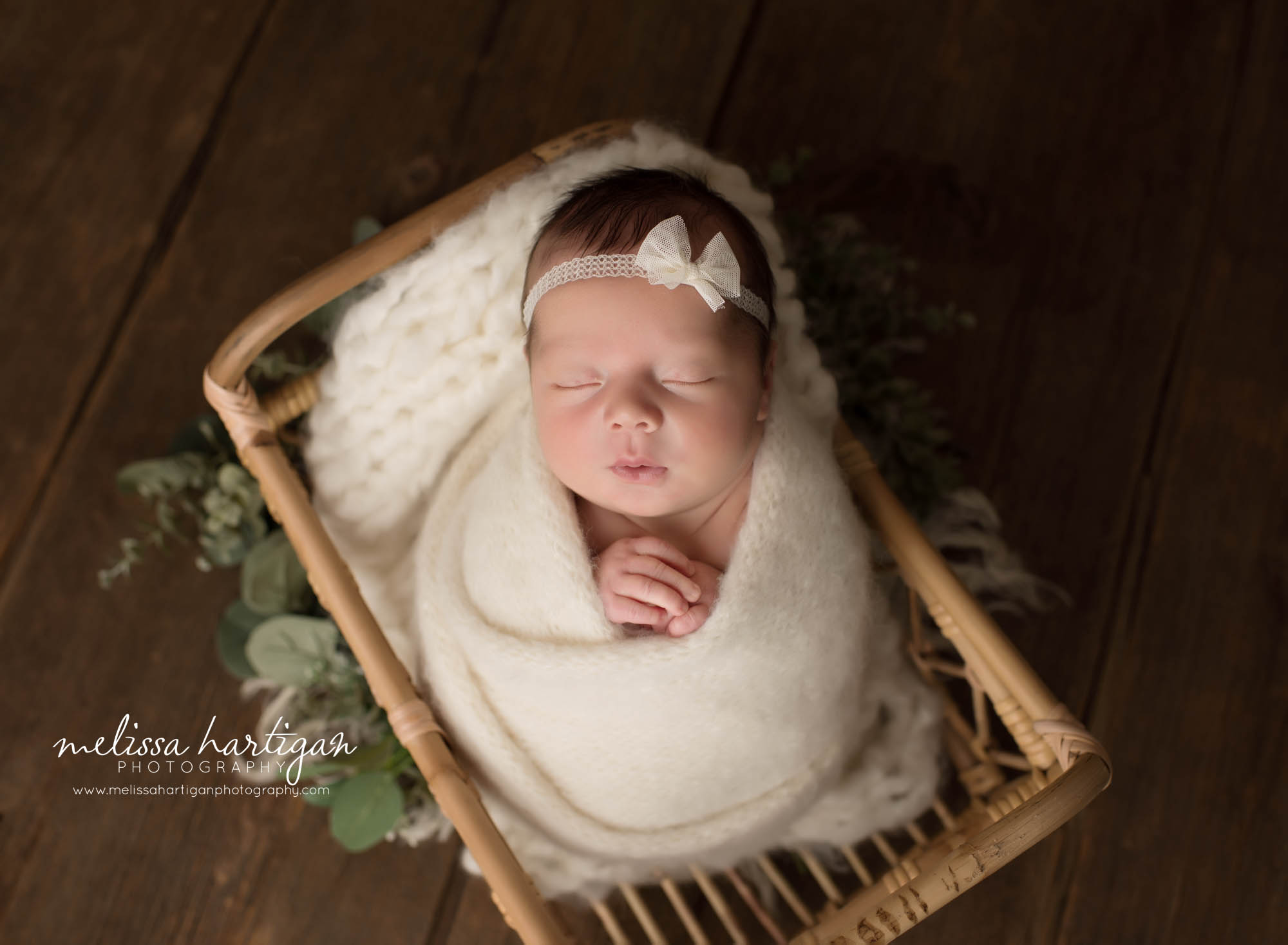 newborn baby girl wrapped in knitted wrap with bow headband