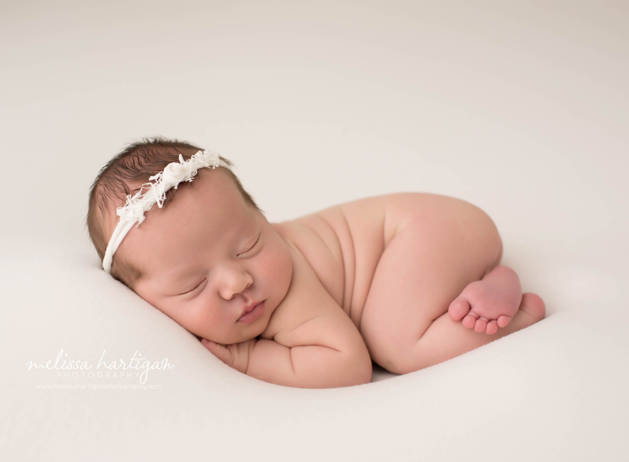 newborn baby girl posed on tummy wearing cream headband ct newborn photography