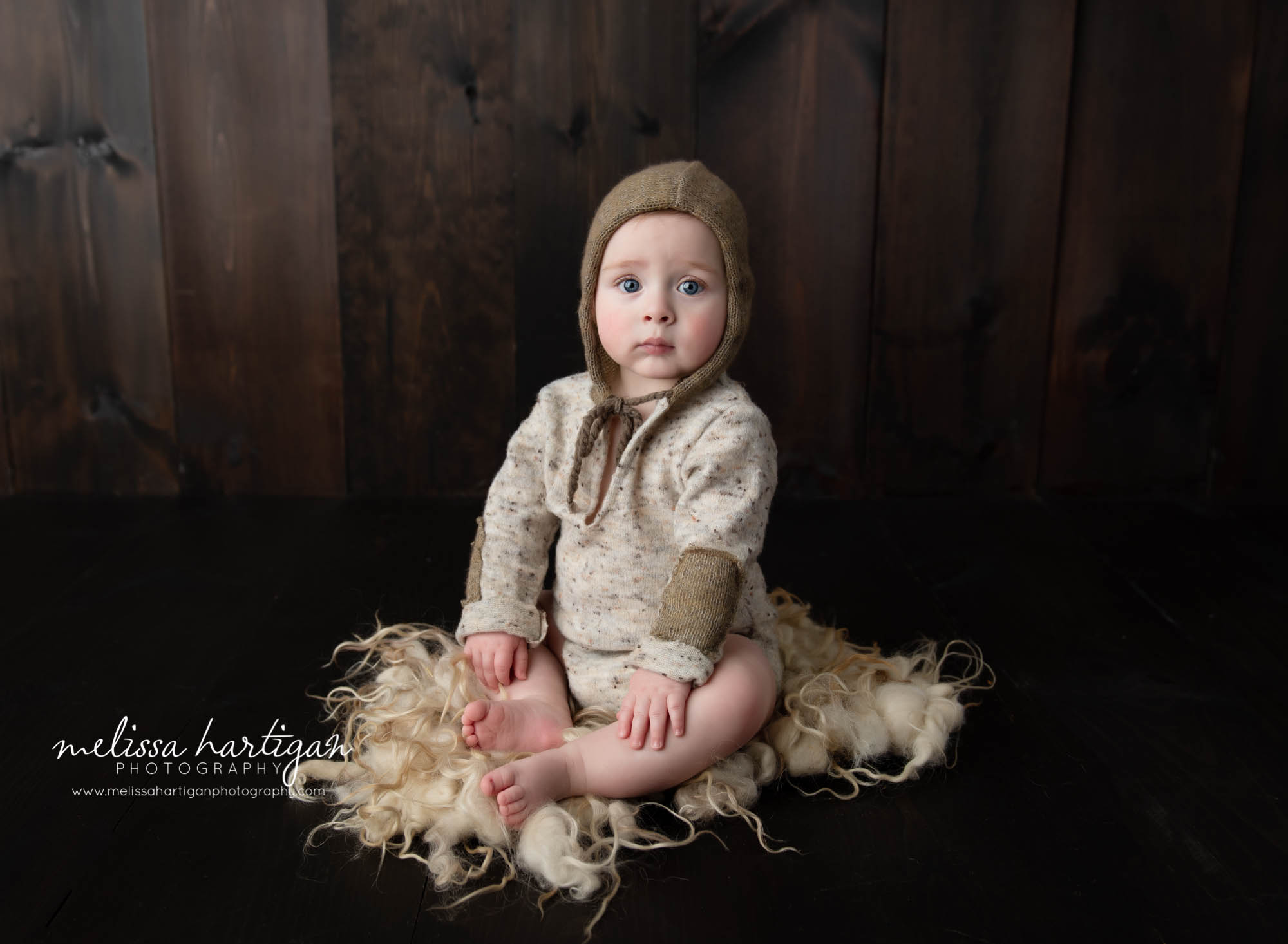 baby boy sitting on fluff wearing sitting up baby boy milestone photography outfit and knitted bonnet connecticut baby photography
