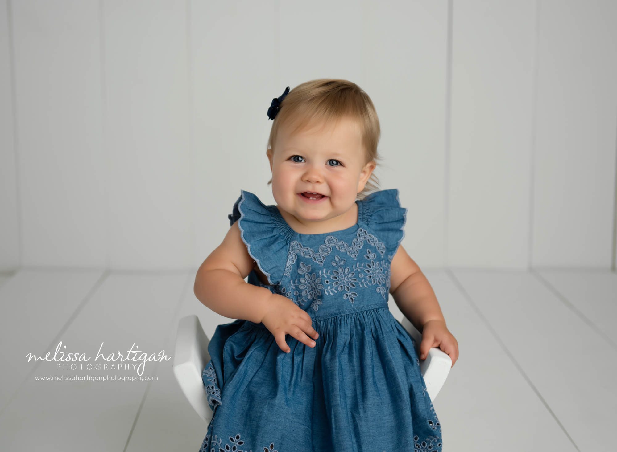 baby girl sitting on curbed wooden bench wearing blue dress hartford county baby photography