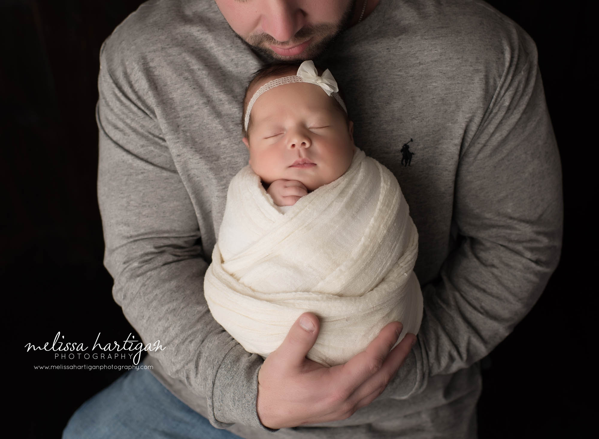 dad holding newborn daughter wrapped in cream knitted wrap