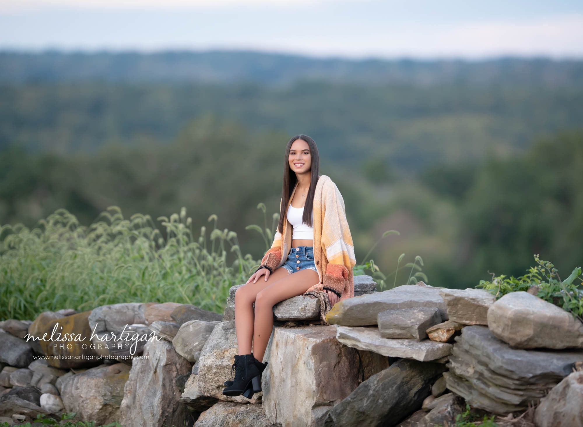 girl sitting on rocks for senior portrait photography session in connecticut