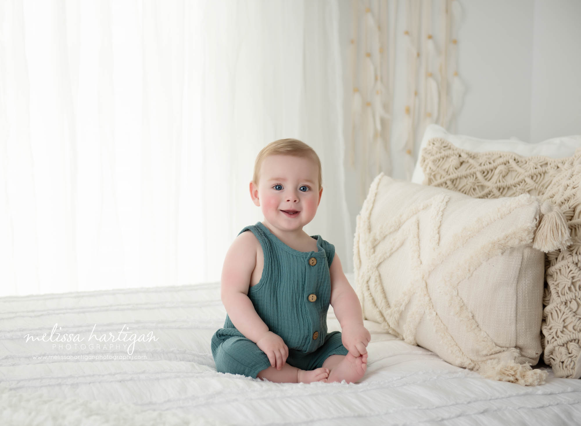 baby boy sitting on bed wearing green baby outfit unionville CT baby photography