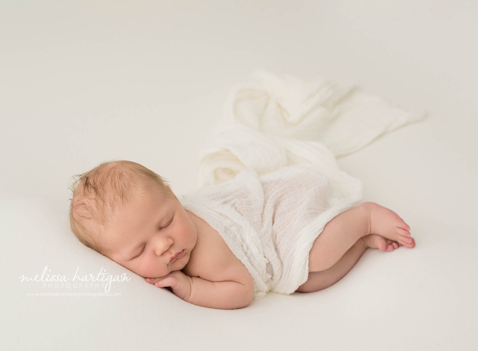 newborn baby boy posed on side with white layer wrap
