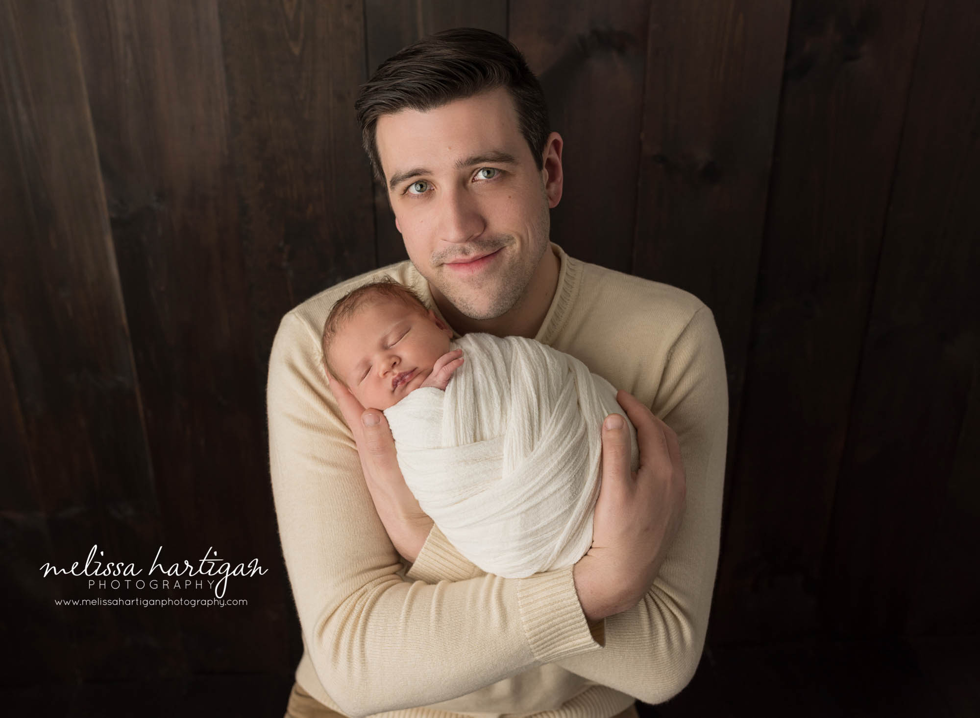 dad holding newborn son in parent pose newborn photography ct studio
