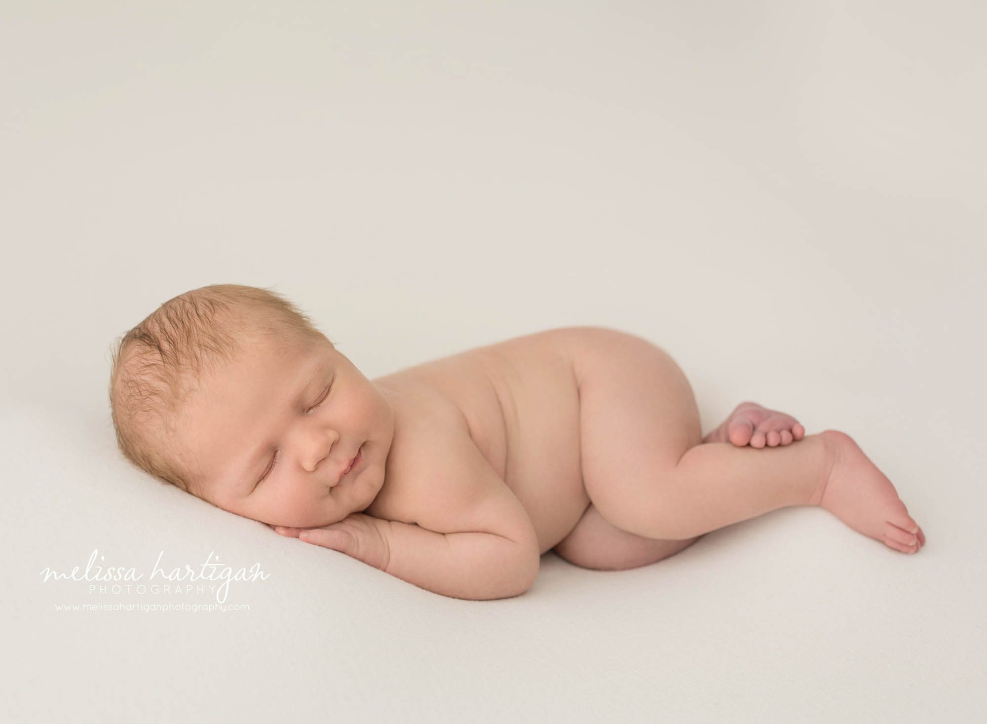 newborn baby boy posed on side with hand under chin posed on white backdrop newborn photography brooklyn ct