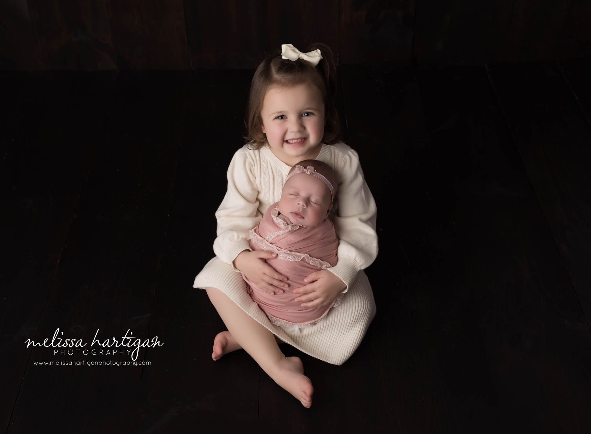 big sister holding newborn baby sister in sibling pose newborn photography session