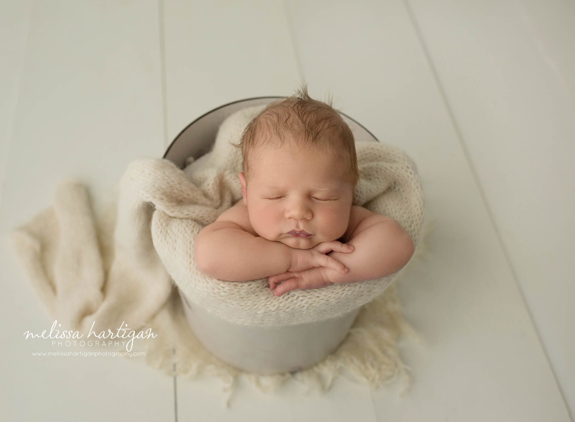 newborn baby boy posed in bucket with cream layer wrap newborn photographer brooklyn ct