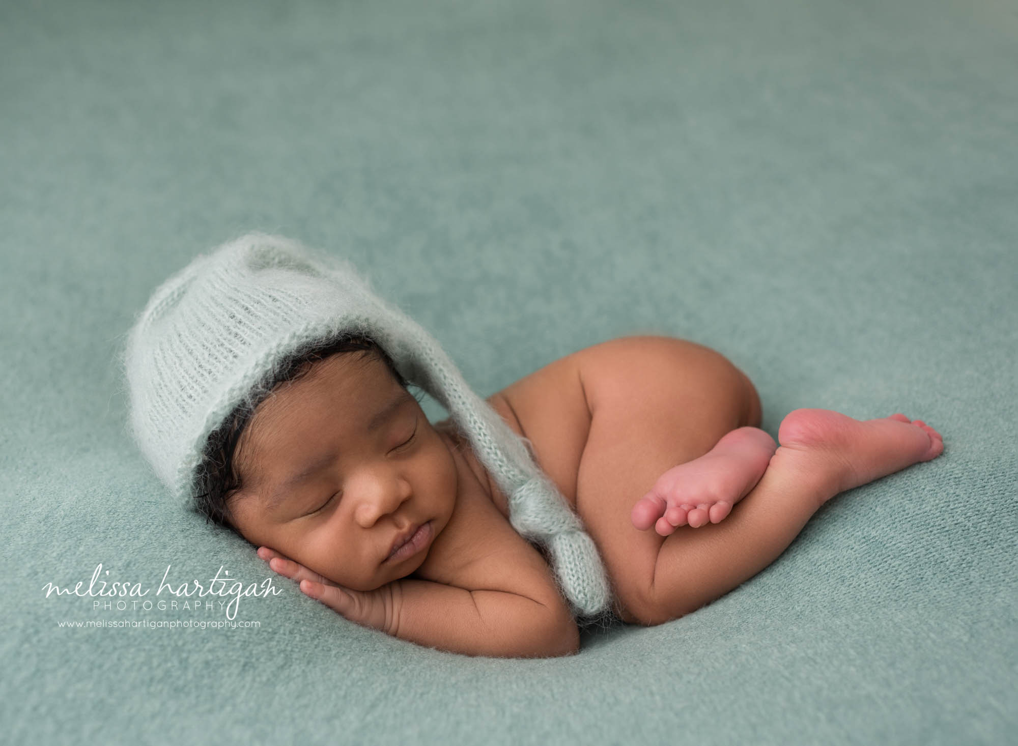 newborn abby boy posed on tummy wearing knitted sleepy cap