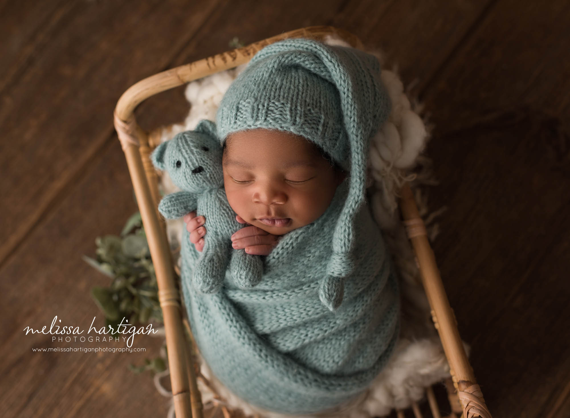 newborn baby boy wrapped in green knitted wrap with knitted sleepy cap and matching teddy