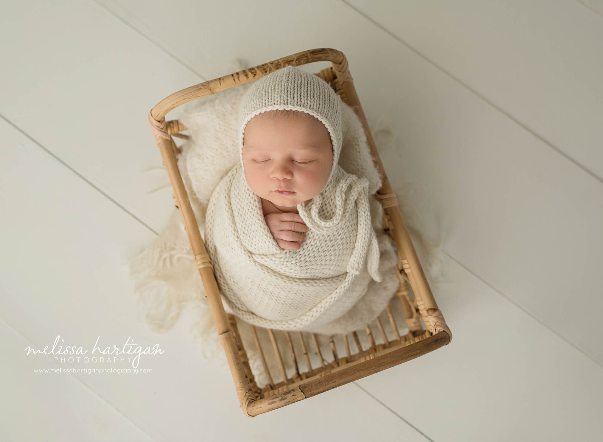 newborn baby boy wrapped in cream wrap posed in basket