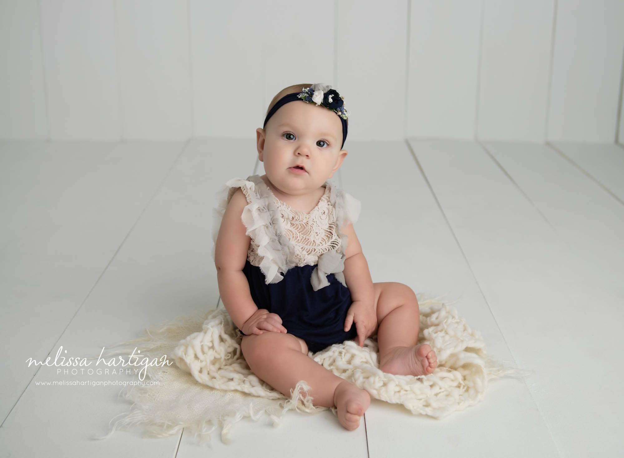 baby girl sitting on wooden boards and cream layer wrap in baby photography CT studio
