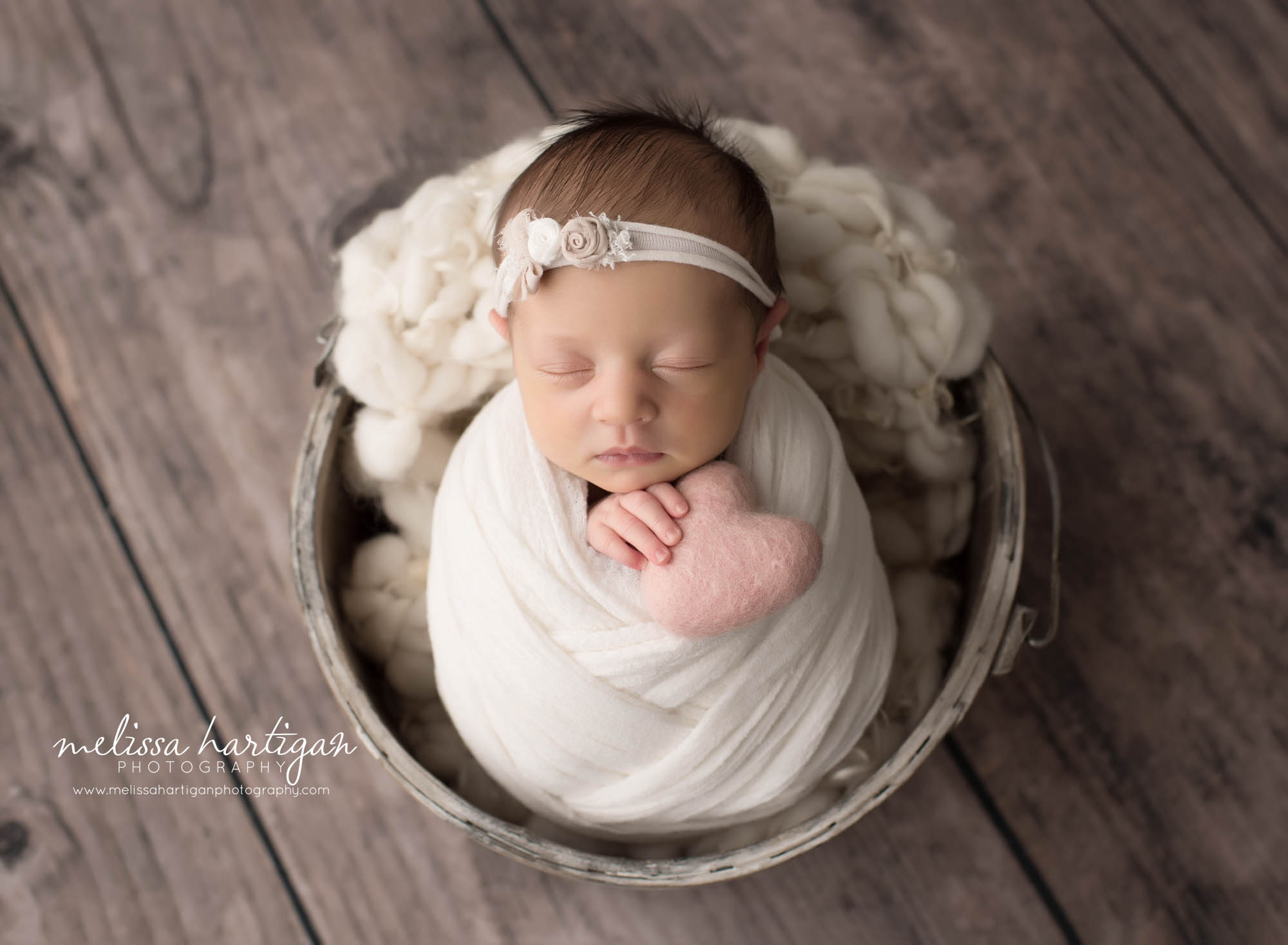 newborn baby girl posed in bucket holding pink felted heart