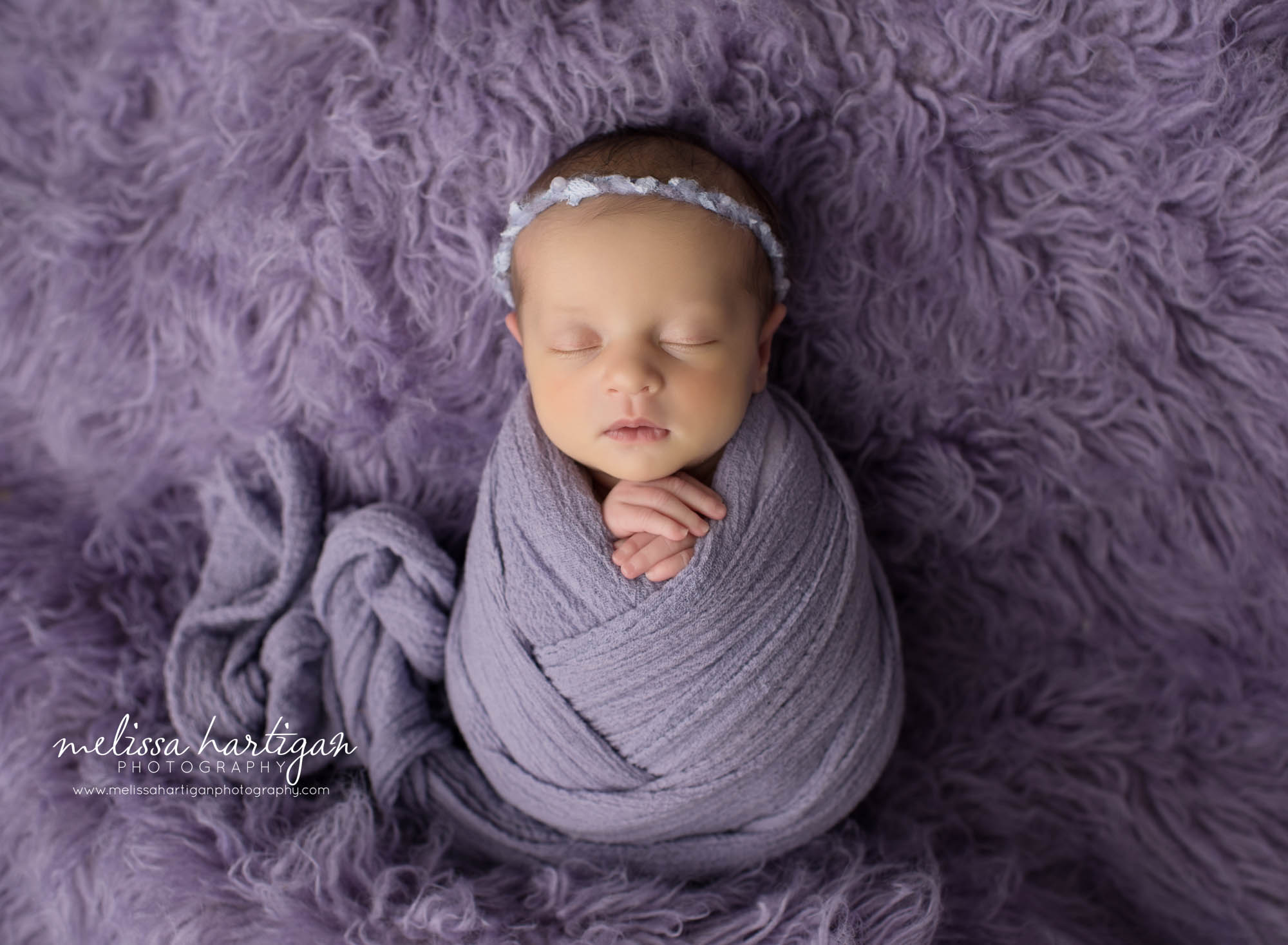 newborn baby girl wrapped in purple wrap posed on purple flokati rug CT baby photographer