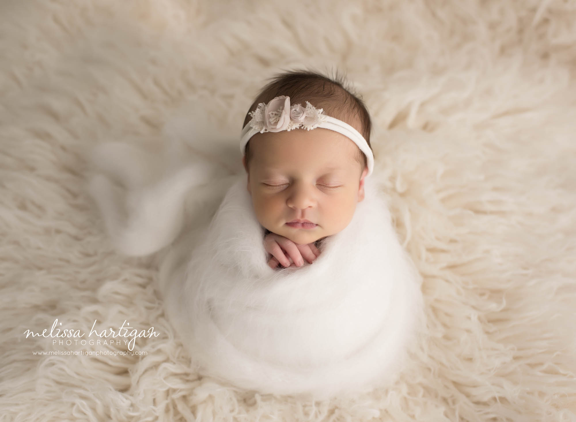 newborn baby girl wrapped in cream white knitted wrap posed on cream flokati rug CT newborn photographer