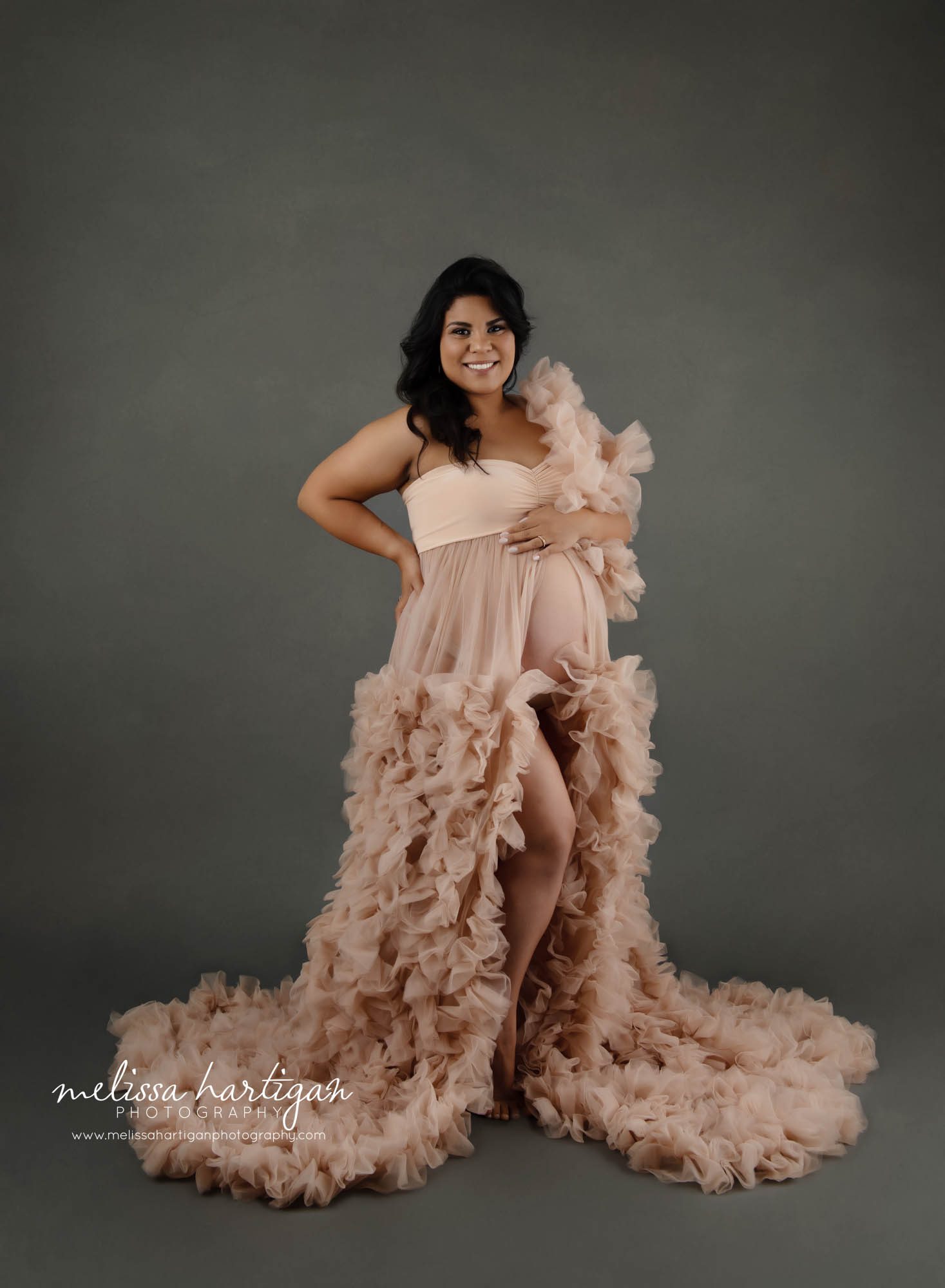 pregnant mom wearing pink ruffled long maternity gown on stop off the shoulder studio maternity