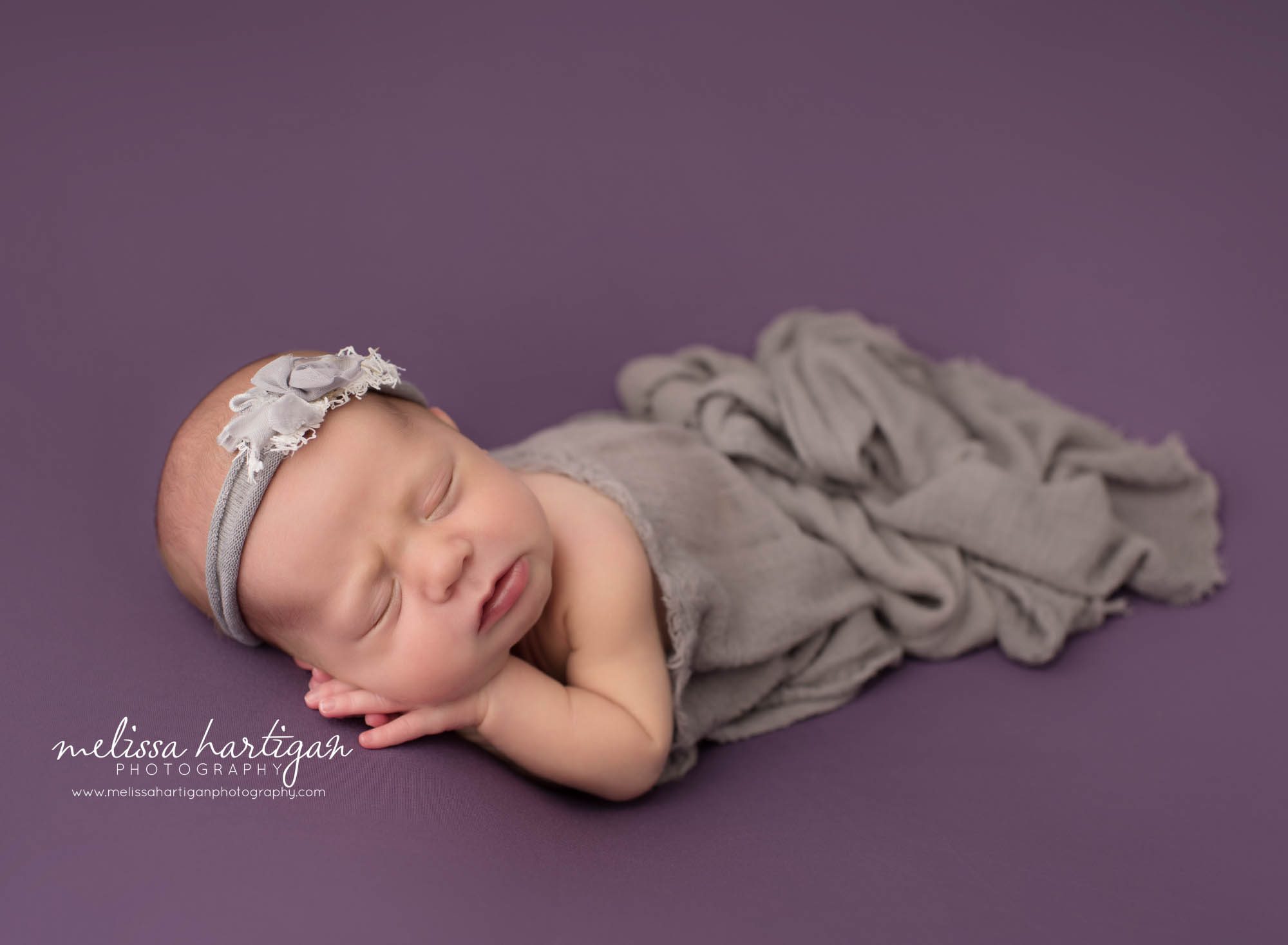 newborn baby girl posed on purple backdrop with gray draping layer newborn photography litchfield county