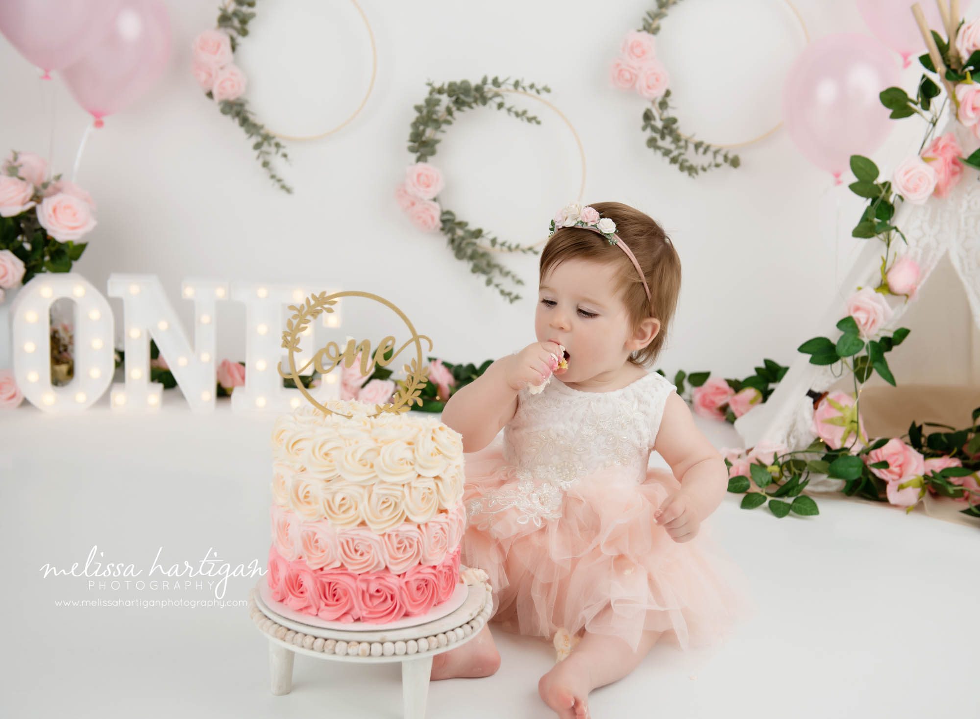 baby girl grabbing to taste pink and cream smash cake