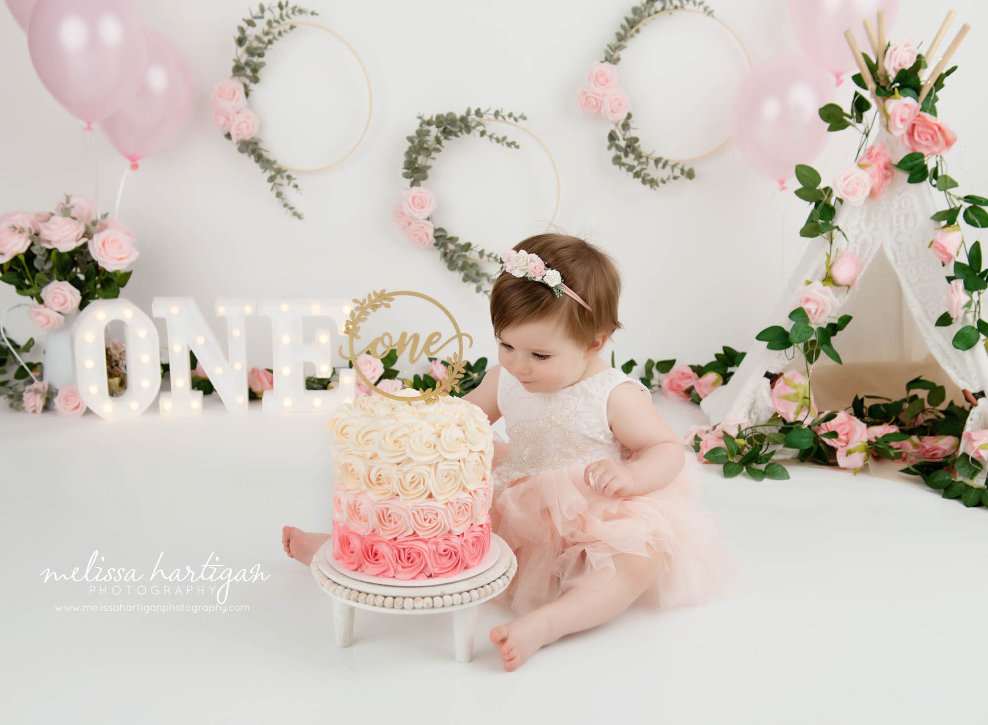 baby girl touching pink and cream smash cake