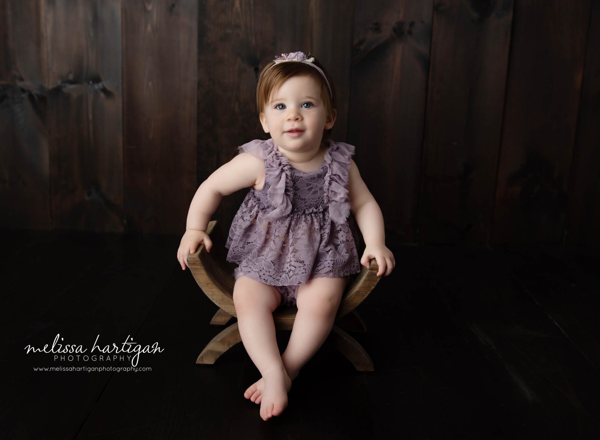 baby girl wearing purple outfit sitting on wooden u-shaped bench west hartford baby photography ct